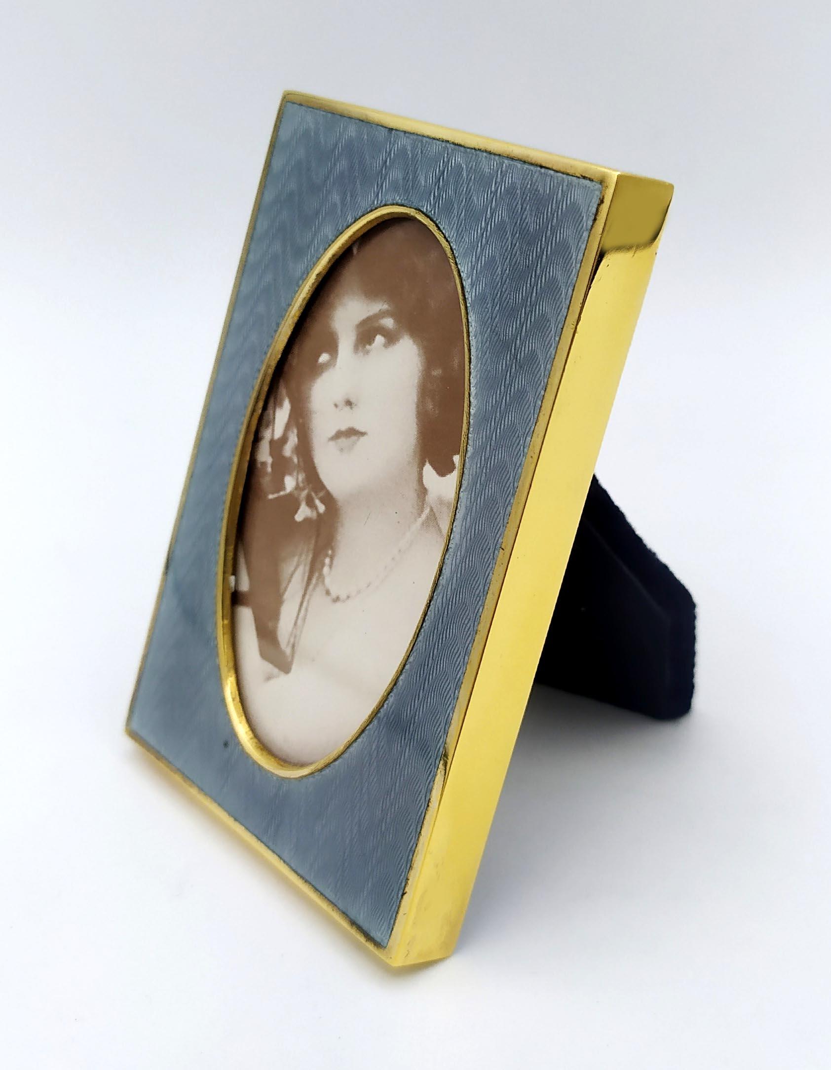 Marco de fotos rectangular para oval en plata de ley 925/1000 dorada con esmalte al fuego translúcido sobre guilloché, estilo inglés, principios del siglo XX. Exterior cm. 6 x 9, interno oval cm. 3.8 x 6.7. Peso gr. 65. Diseñada por Renato Salimbeni