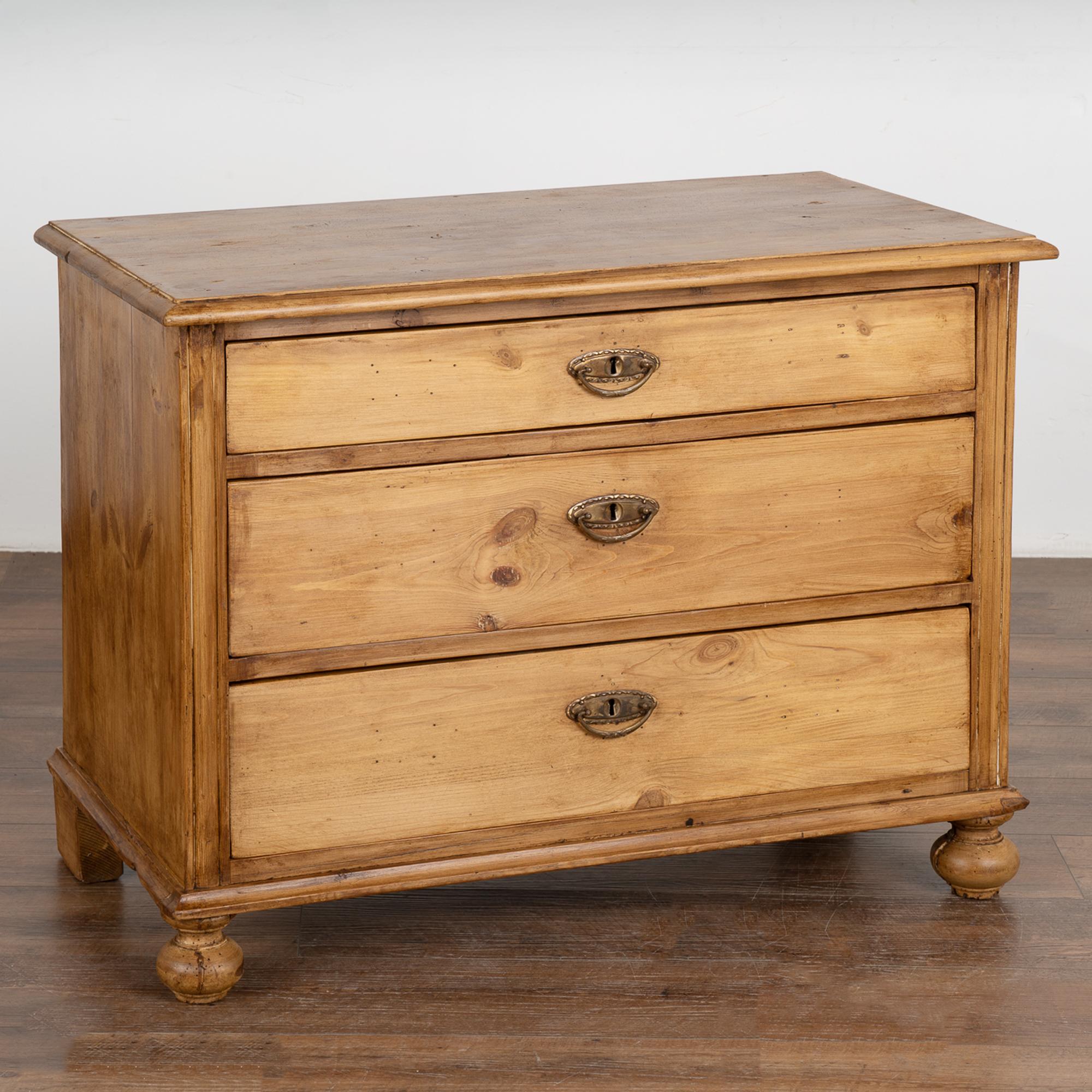 This small pine chest of three drawers has been given a waxed finish, bringing out the warmth of the pine. 
Note the craftsmanship in the dovetail joints of the drawers and original bun feet in front, block feet in rear.
Restored, this chest is