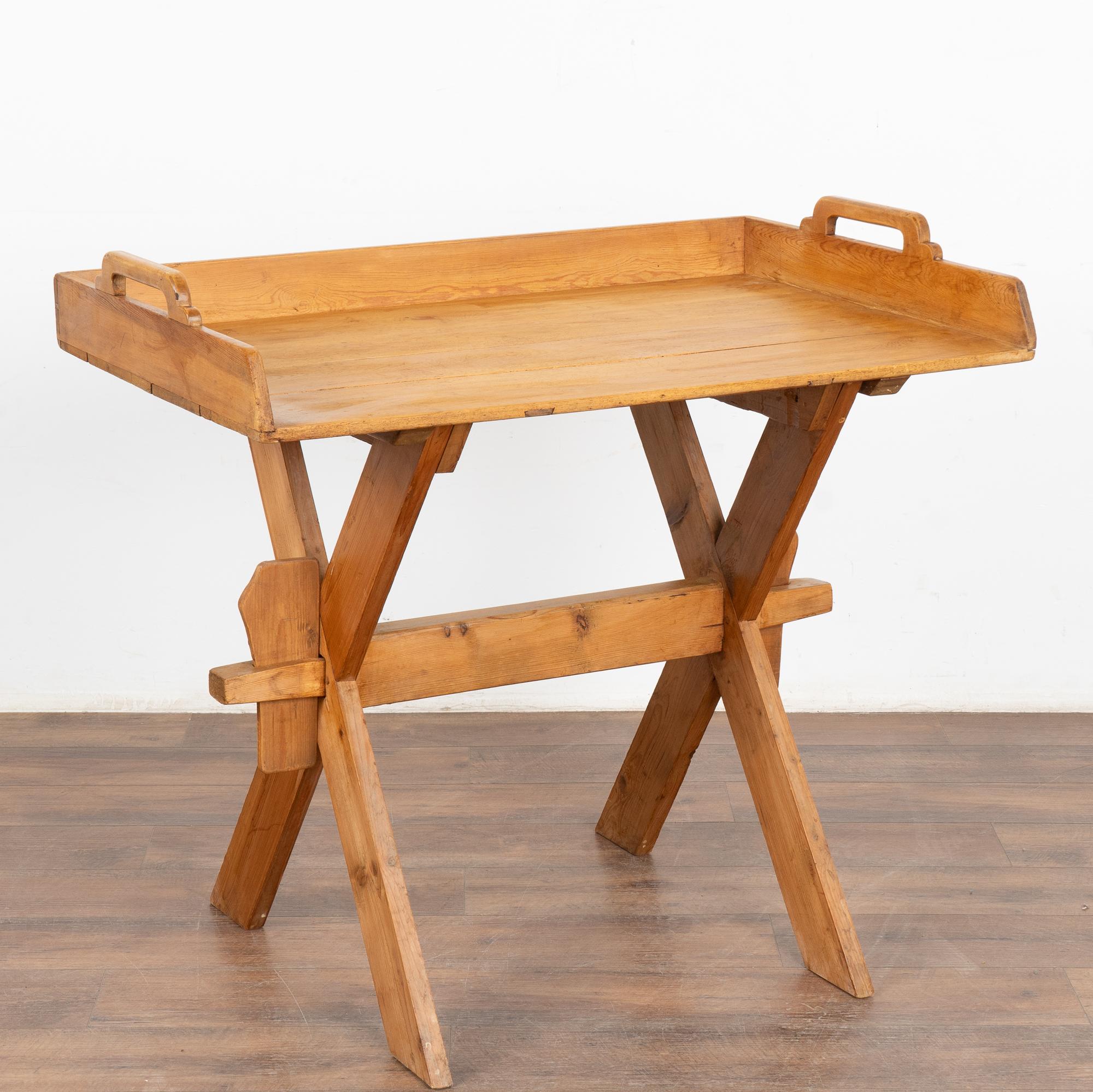 Small pine side table with tray top resting on trestle X base, great to serve as a bar table for drinks.
Restored, strong and stable, this table is ready to be used and enjoyed. Wax finish.
The smaller size makes it adaptable to serve as a side