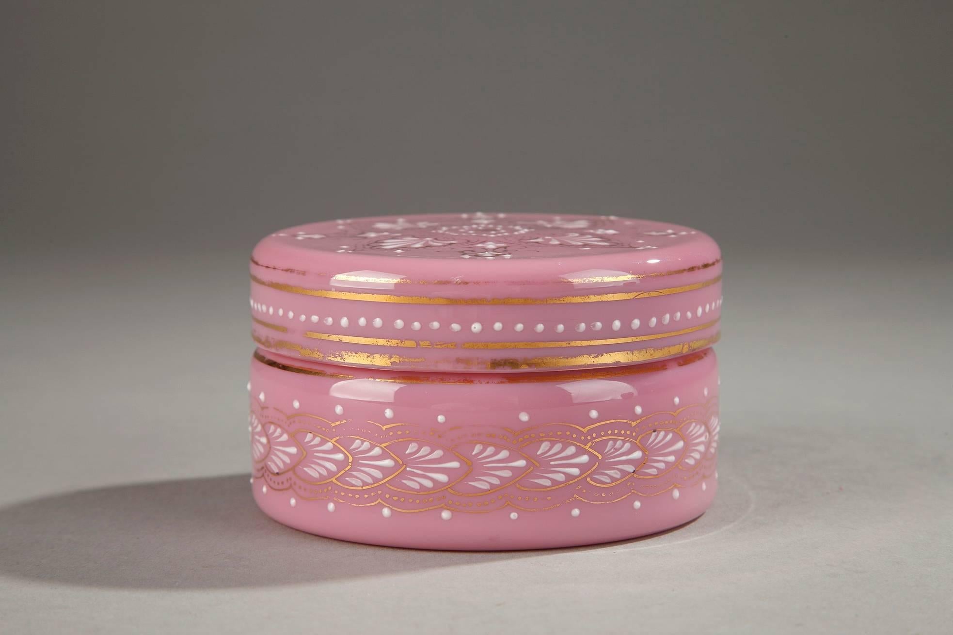 Small, pink opaline box with white enamel decorations of palmettes, small dots, and floral motifs. Thin, gold bands and embellishments accent the lid and body of the box. The box imitates porcelain and the enamel is very intricate. Probably