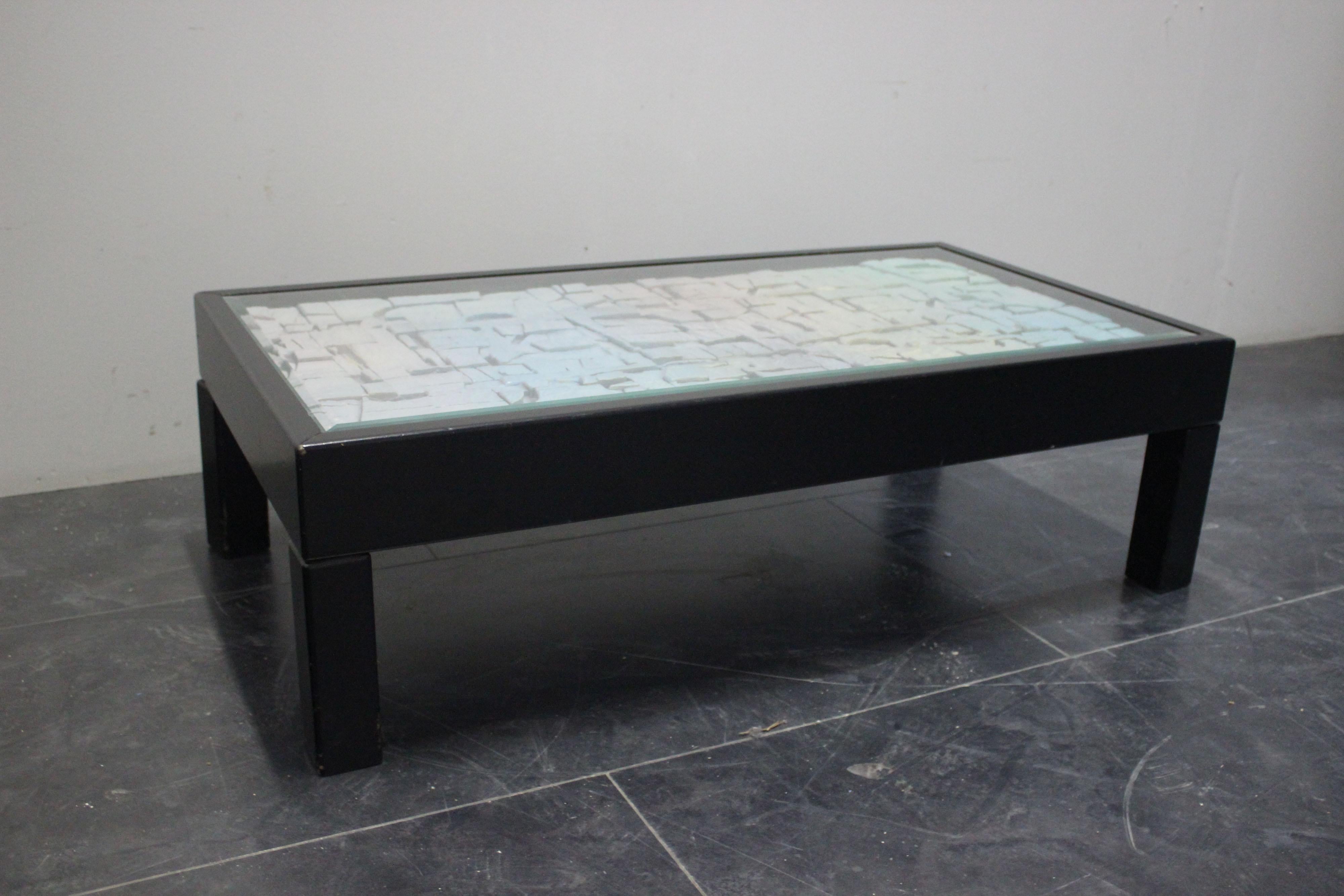 Le style est Space Age et la qualité décorative est élevée pour le plateau de cette petite table des années 70, le corps est en bois laqué noir, sous le plateau en cristal de roche, une plaque en relief au thème d'une possible surface planétaire,
