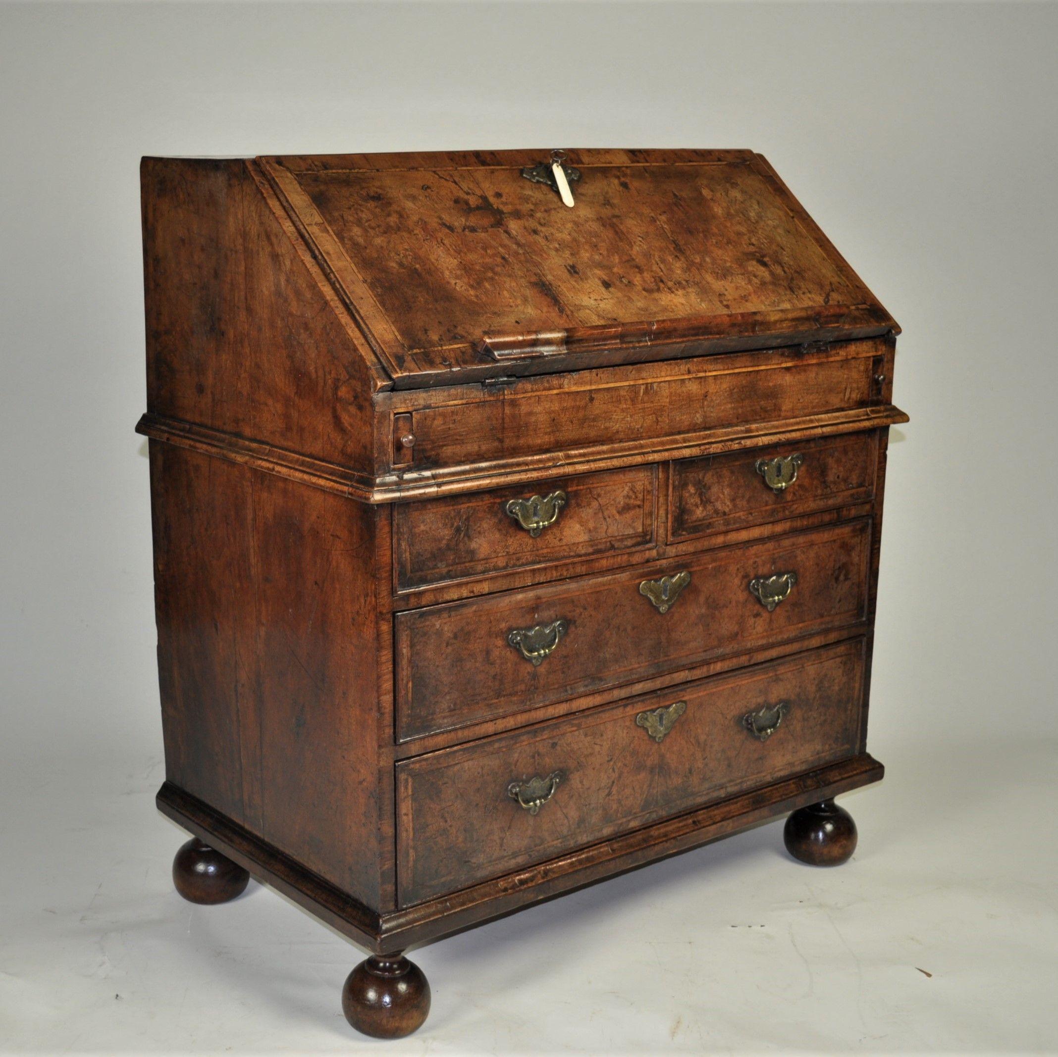 A most enchanting Queen Anne period burr walnut bureau of highly desirable small proportions and superb colour. The herringbone and cross-banded fall enclosing a fully fitted stepped interior with small drawers and central cupboard door all