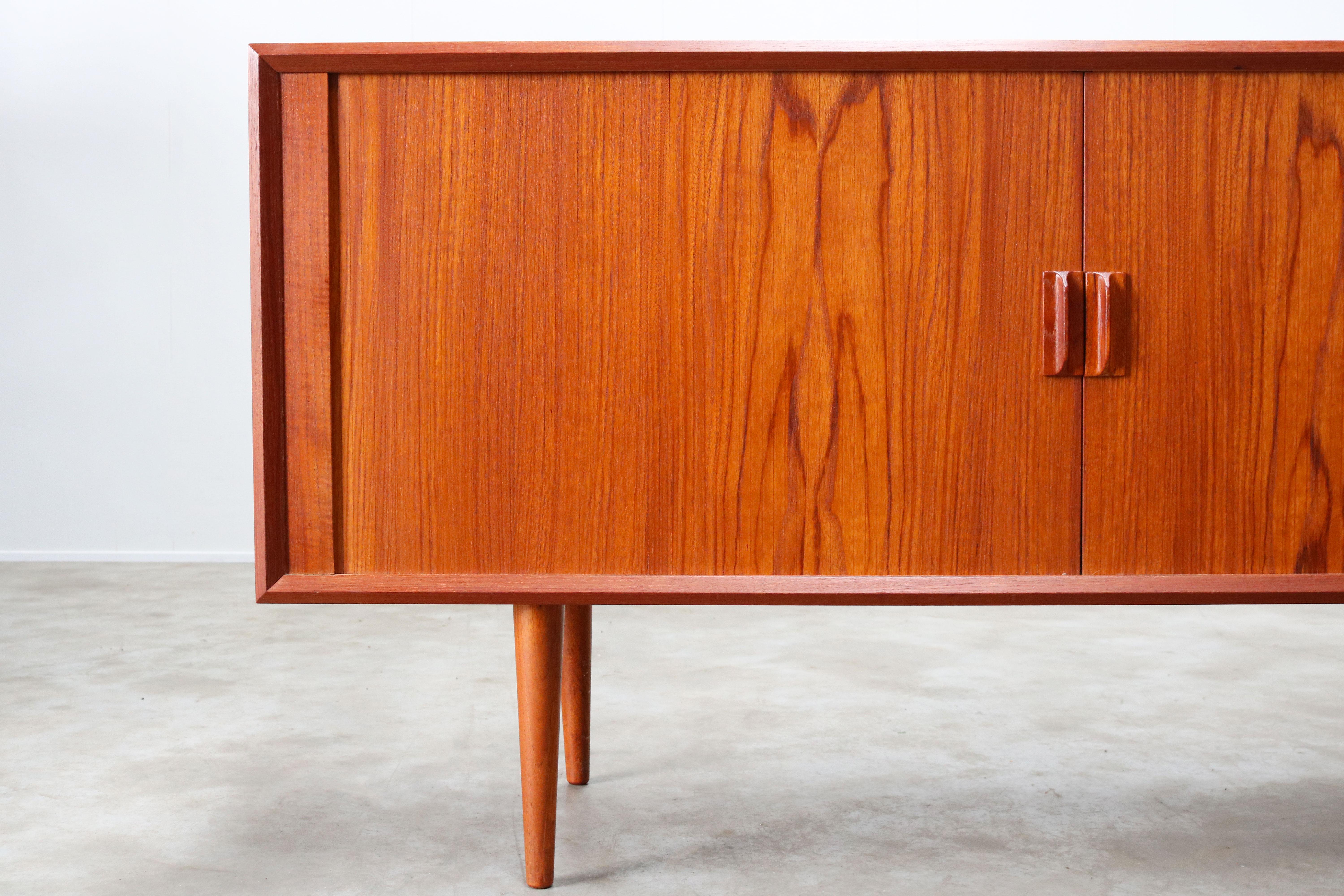 Rare small Danish design sideboard / credenza by Svend Aage Madsen for the Faarup Mobelfabrik in the 1950s. The sideboard has a amazing clean design and small size. The tambour doors disappear completely when opened and the craftsmanship on this