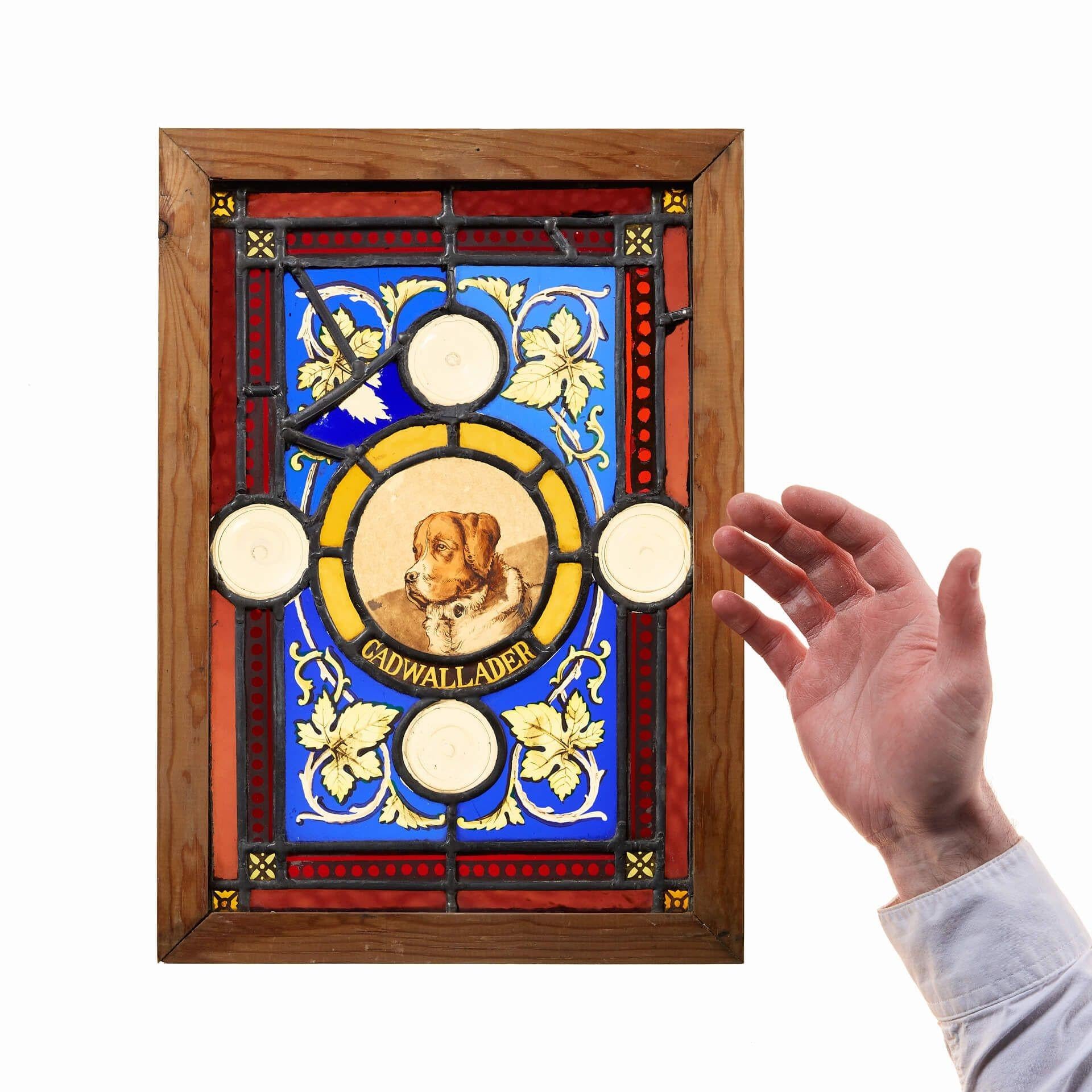 A vibrant small reclaimed stained glass panel of a dog named ‘Cadwallader’.

Skilfully designed, this antique stained glass window details a beloved pet dog surrounded by layered borders of various vivid colours, complimented by clear roundels and