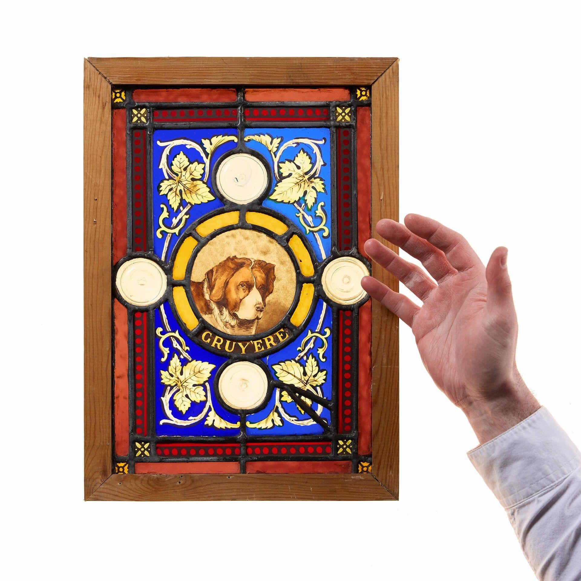 A vibrant small reclaimed stained glass panel of a dog named ‘Cruy'ere’.

Skilfully designed, this antique stained glass window details a beloved pet dog surrounded by layered borders of various vivid colours, complimented by clear roundels and hand