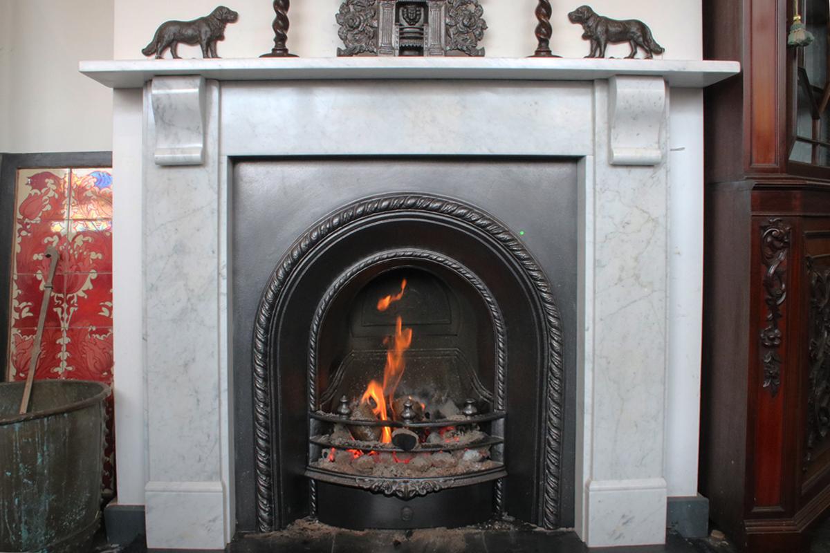 Small reclaimed Victorian Carrara marble fireplace surround with simple geometric corbels supporting the shelf, circa 1870. 

Pictured in situ in our showroom with an original Victorian cast iron arched insert.