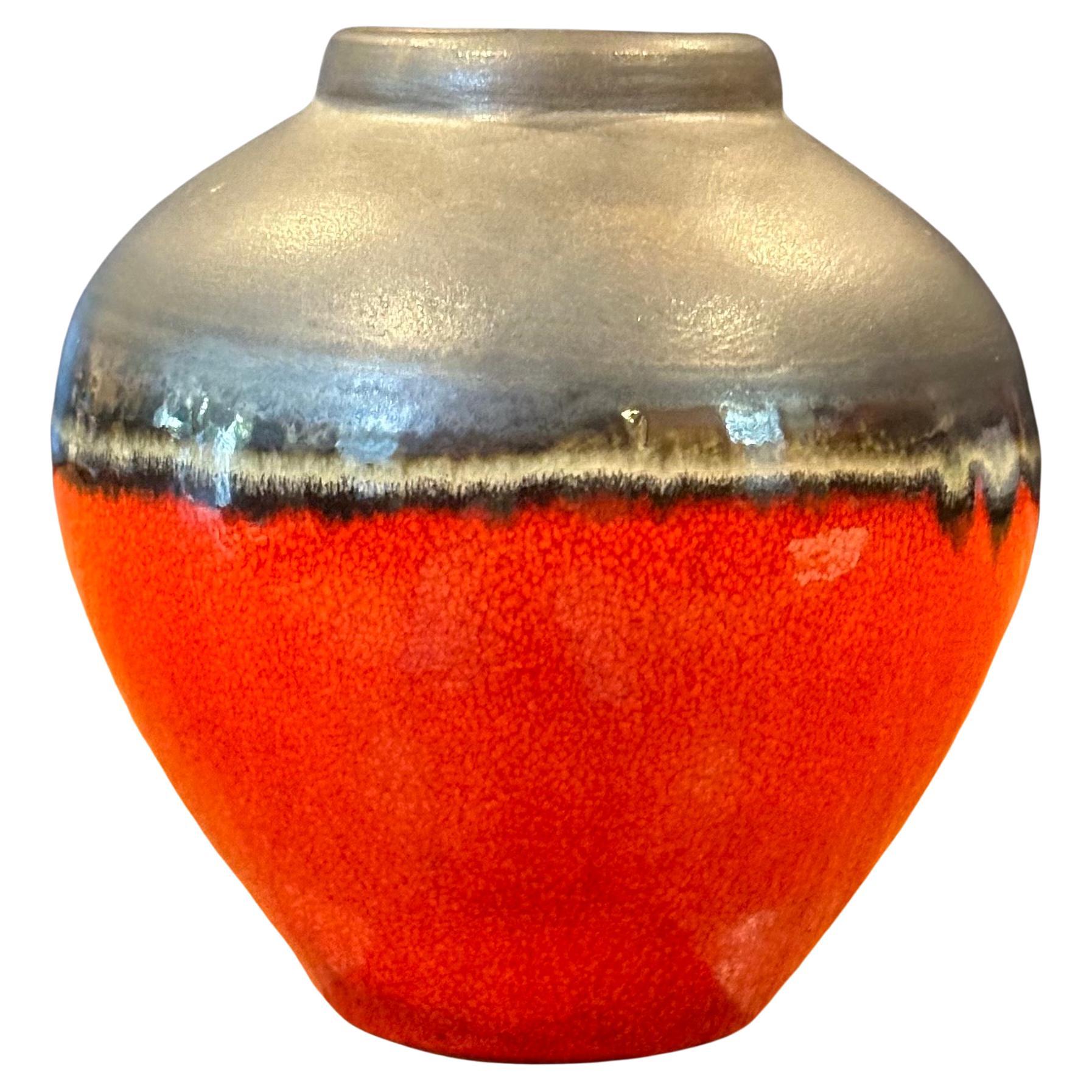 A great looking small red lava glazed vase, circa 1980s. The vase has a dark brown base with a bright red lava glaze and measures 4.25