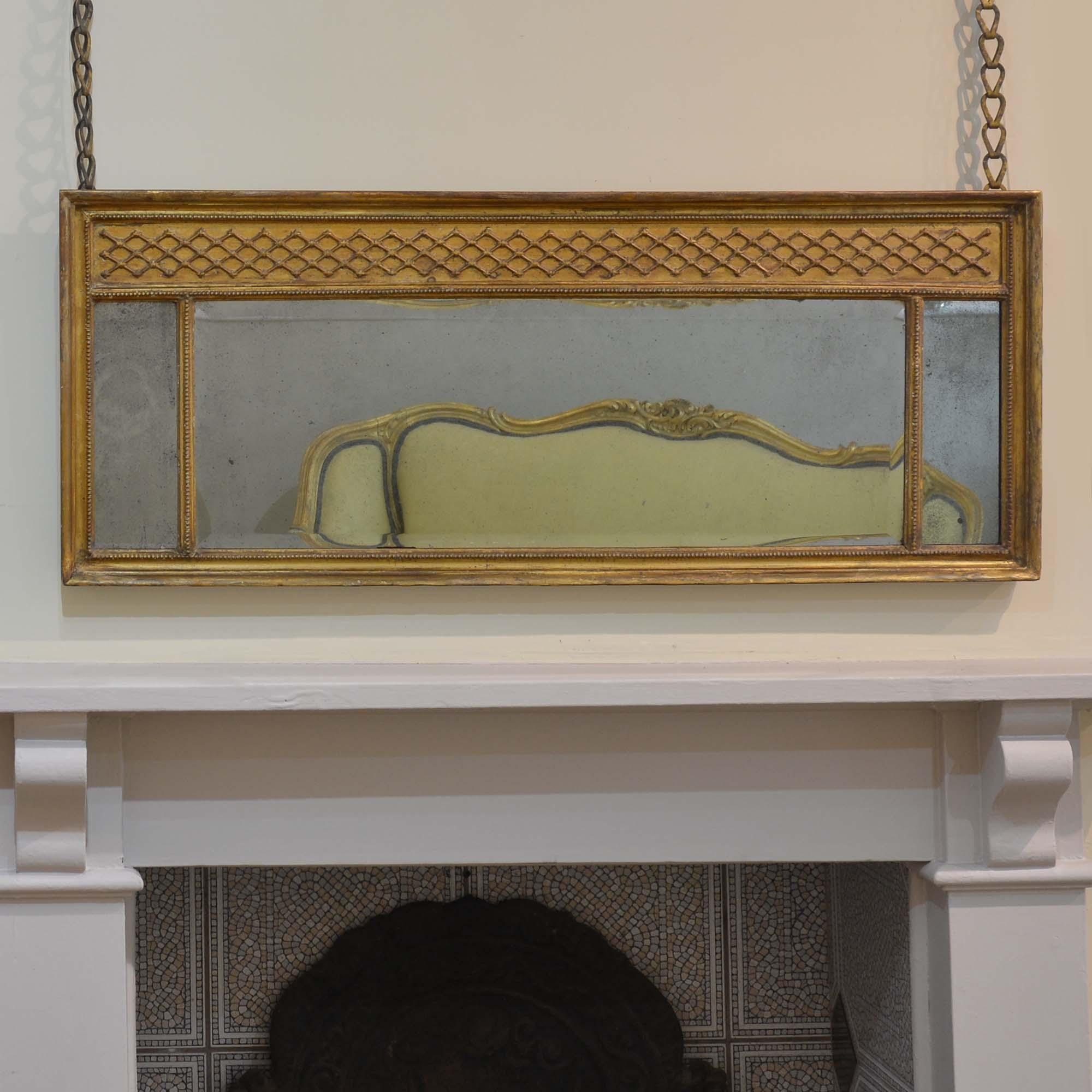 Piccola specchiera Regency in legno dorato
Trittico di piatti a specchio, ciascuno con foxing, il piatto centrale con bordi smussati.  Decorazione a traliccio modellata sopra e su una cornice modellata.  La doratura originale con toni tenui e il