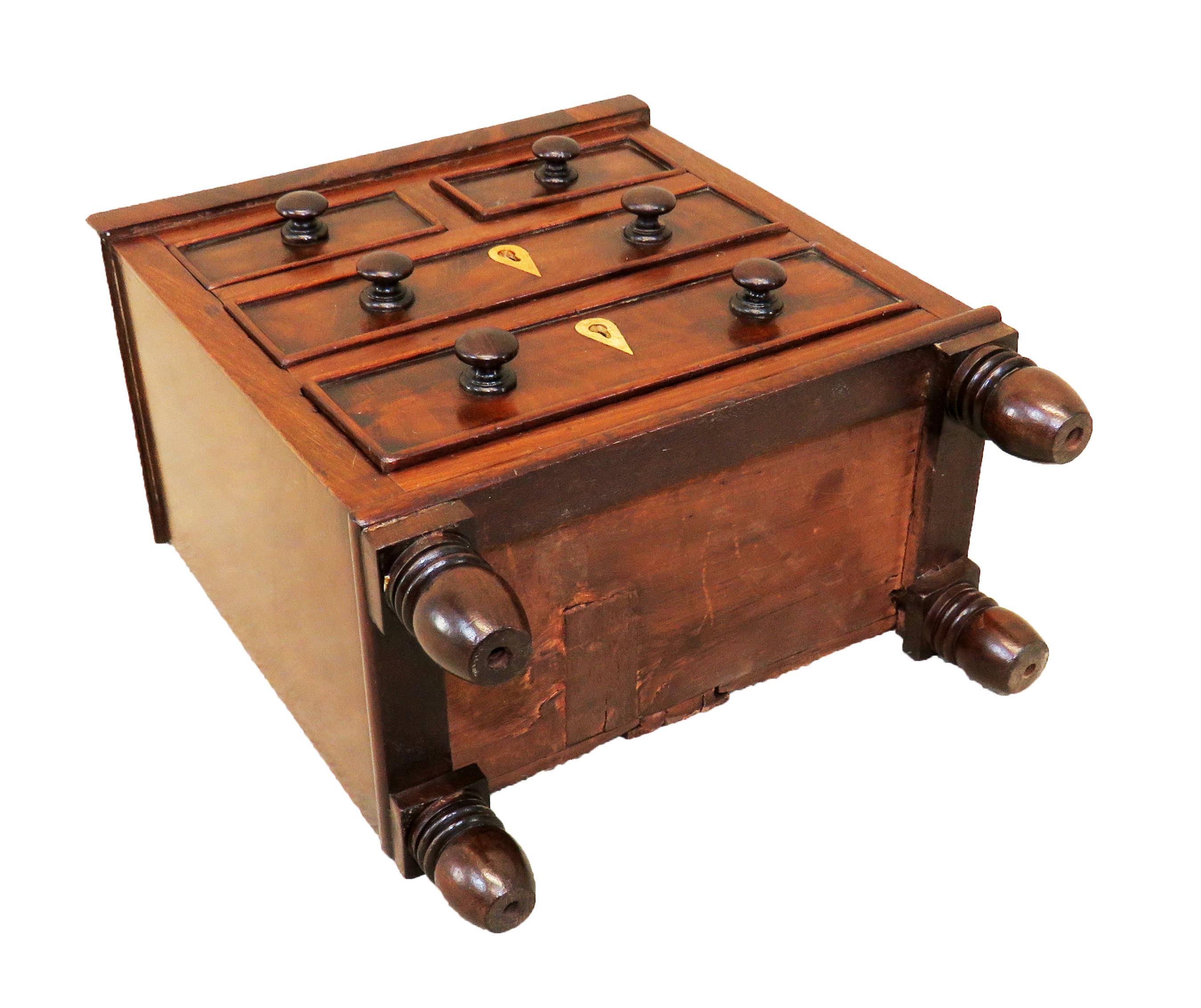 A late Regency mahogany miniature chest of
small proportions having well figured top over
two short and two long drawers retaining
original wooden knobs and original
turned feet

(Often much debate is had as to whether miniature furniture was