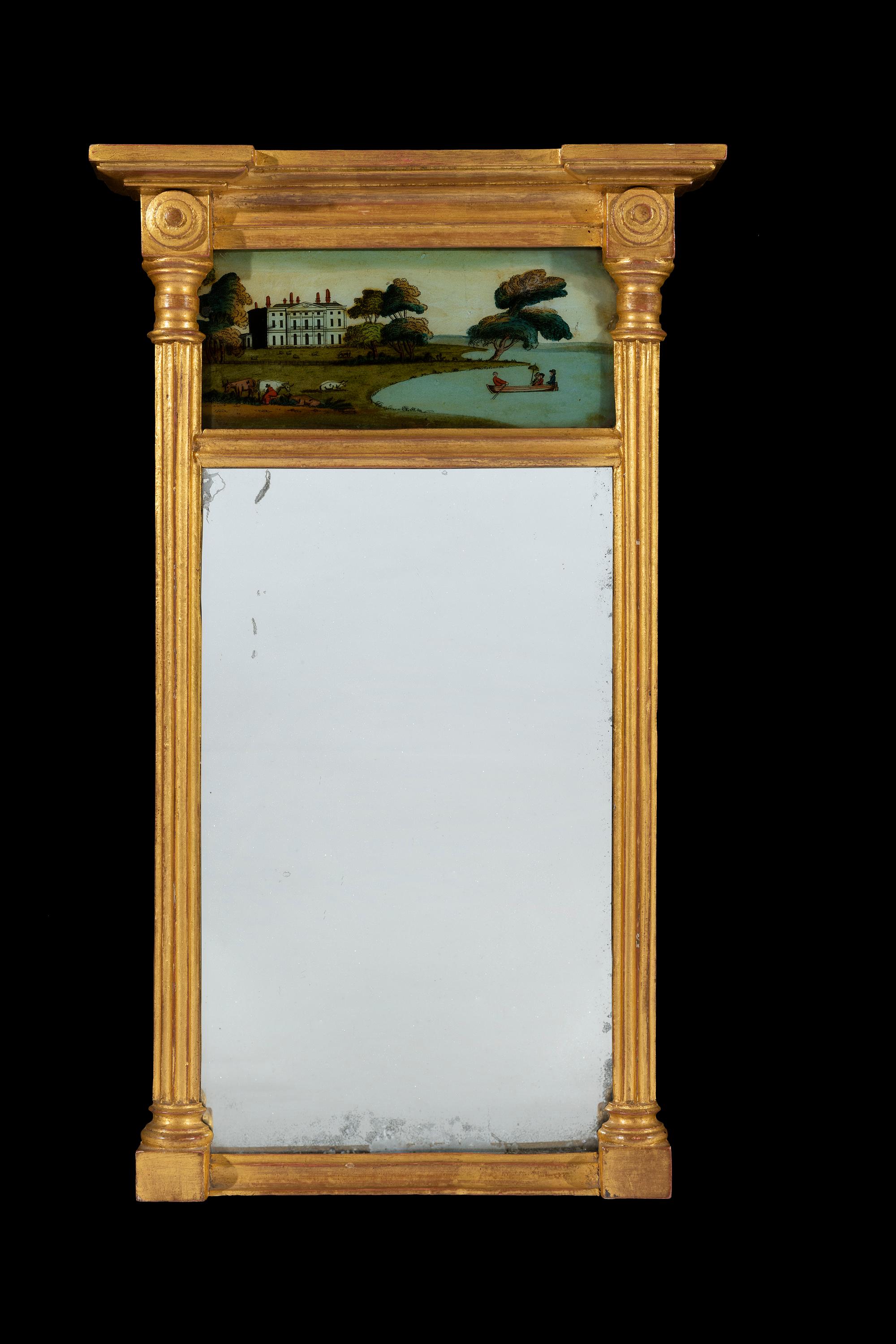 The diminutive giltwood mirror has an eglomisé plate depicting figures on a lake by a large Georgian house. The reeded columns flank the original plate glass mirror.