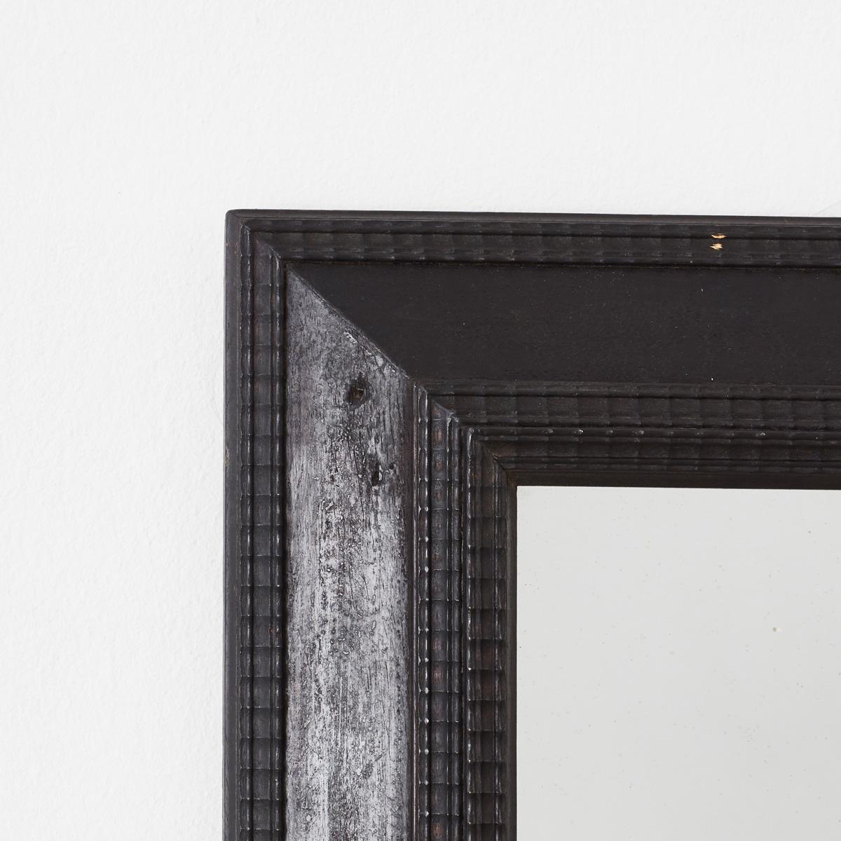 Made in Italy well over one hundred years ago, the ebonised wooden frame of this striking ripple frame mirror is crafted in an 17th and 18th Century Dutch style. Its surface is intricately detailed and textured with carved patterns of indentations