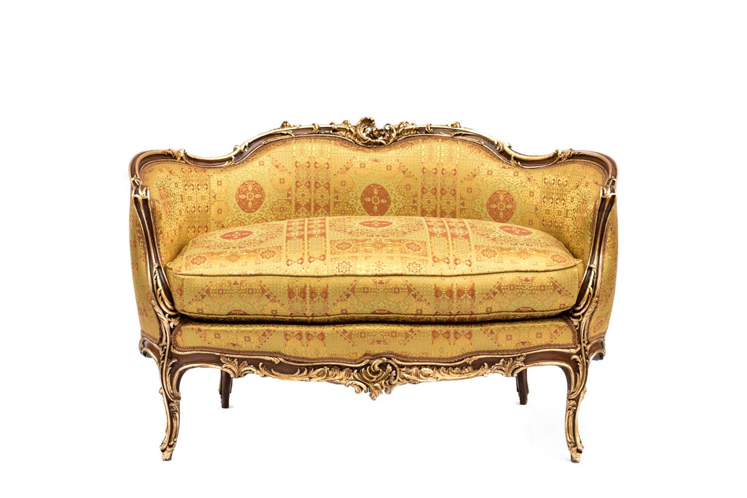 Small Rocaille style sofa in natural carved walnut with gilt highlights. It stands on four cabriole legs and uprights and crosspieces are sinuous and scalloped. Rich Rocaille ornamentation on the carved wood, such as crètes de coq, foliage and