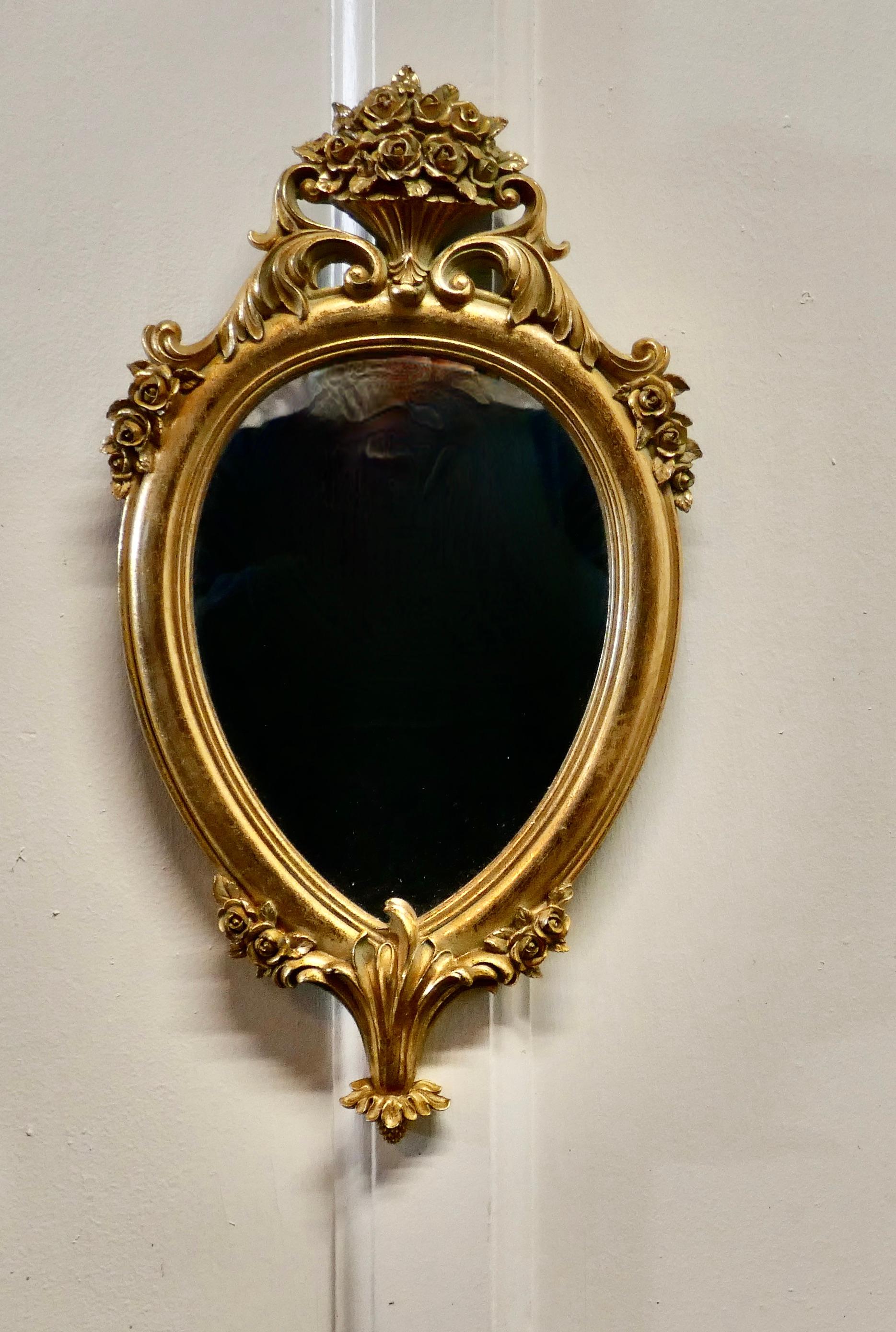 Small rococo gilt wall mirror

The mirror has an exquisite gilt frame in the rococo style, it has a teardrop shape and decorated with a vase of roses at the top more flower at the bottom
The mirror is 10” wide and 17” tall
NV220.