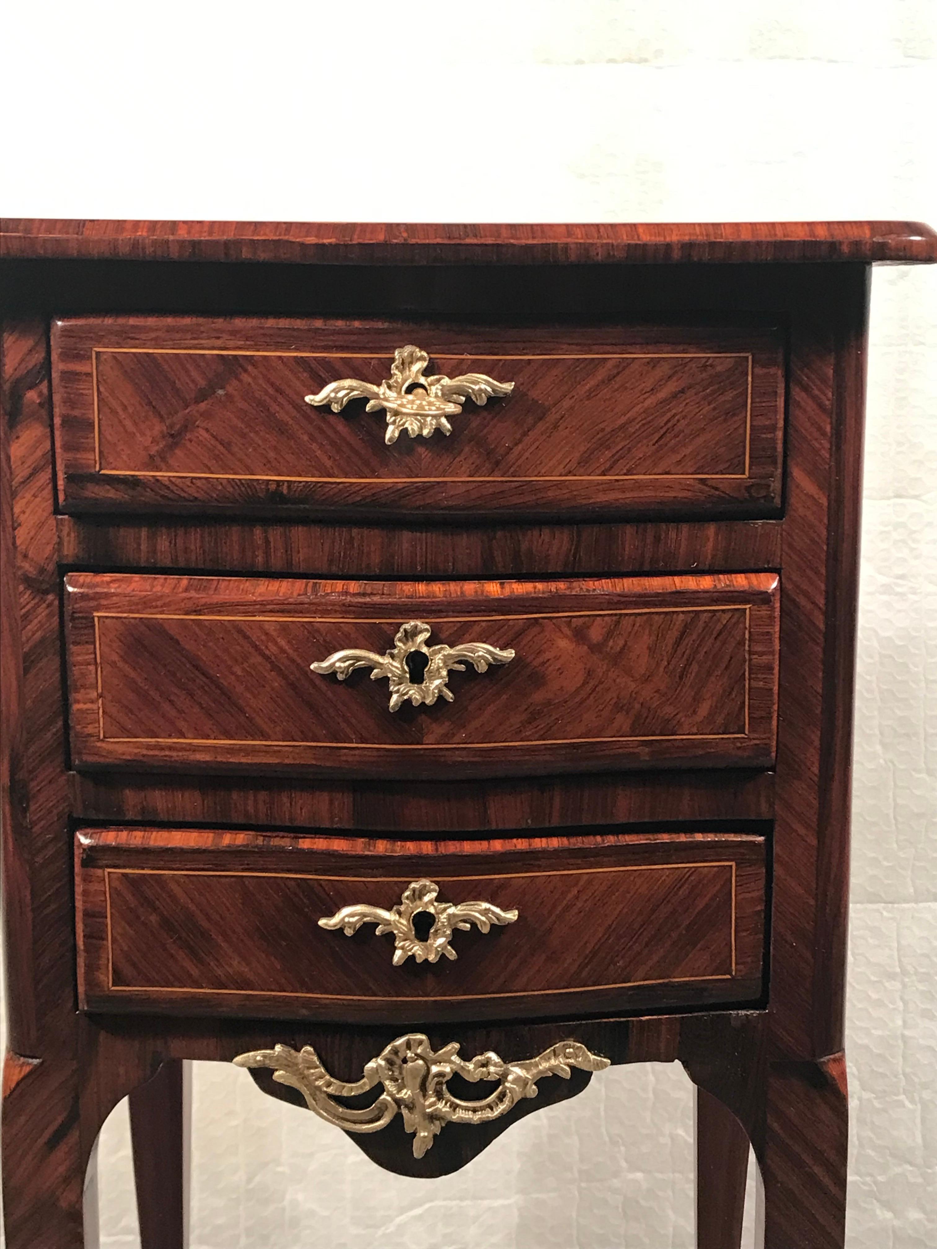 Small Rococo style chest of drawers or nightstand, France 19th century. This beautiful small dresser has a gorgeous kingwood veneer and is decorated with Rococo Style bronze fittings. It comes fully refinished with a shellac polish, these extra