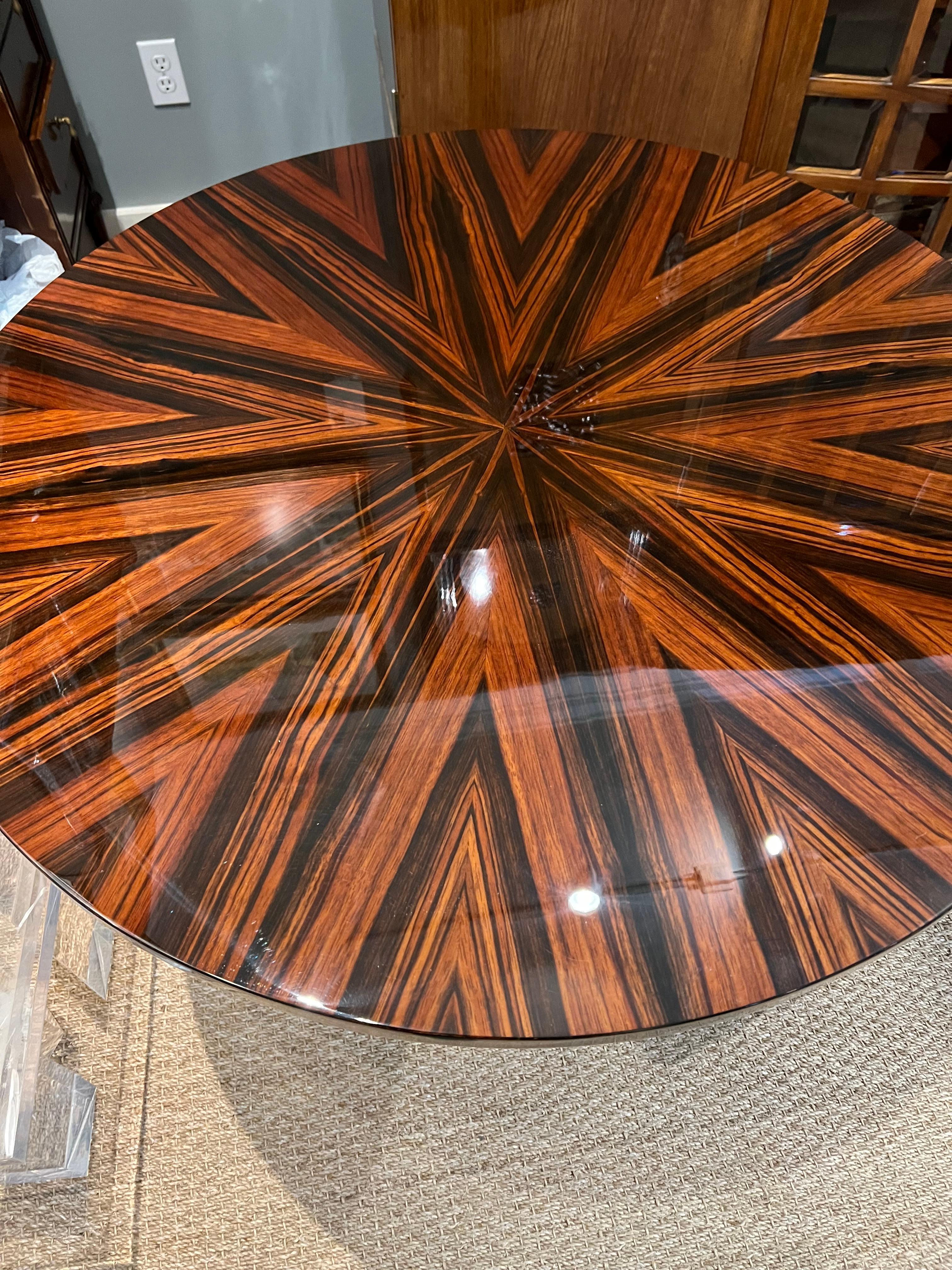 Der Tisch ist aus Makassarholz gefertigt. Die Tischplatte ist an der Unterseite mit einem Messingband verziert. Die Tischplatte ist hochglanzpoliert, um die schöne Holzmaserung zu präsentieren. Er ruht auf 3 Beinen, die am Boden miteinander