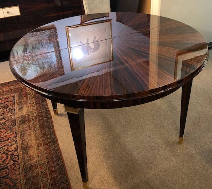 Beautiful table made out of Macassar wood, displaying nice wood grain on the table top. Table top has 2 additional leafs, 16” each. 
Table rests on 4 elongated slim legs that have brass decorative elements on top and the bottom of the each leg.