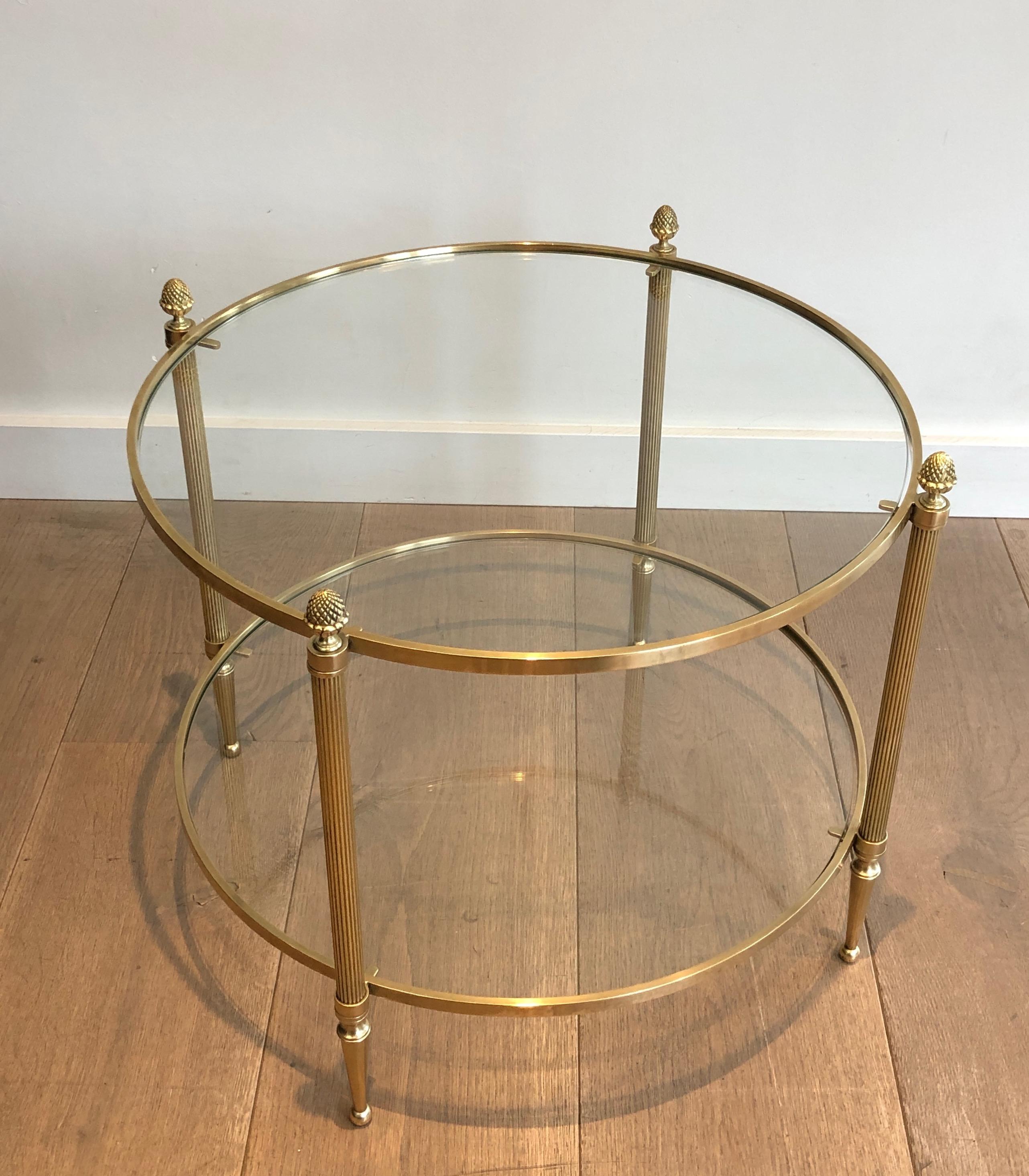 This nice and rare small round coffee table is made of brass with glass shelves and bronze finials. This is a French work by famous Maison Baguès. Circa 1940