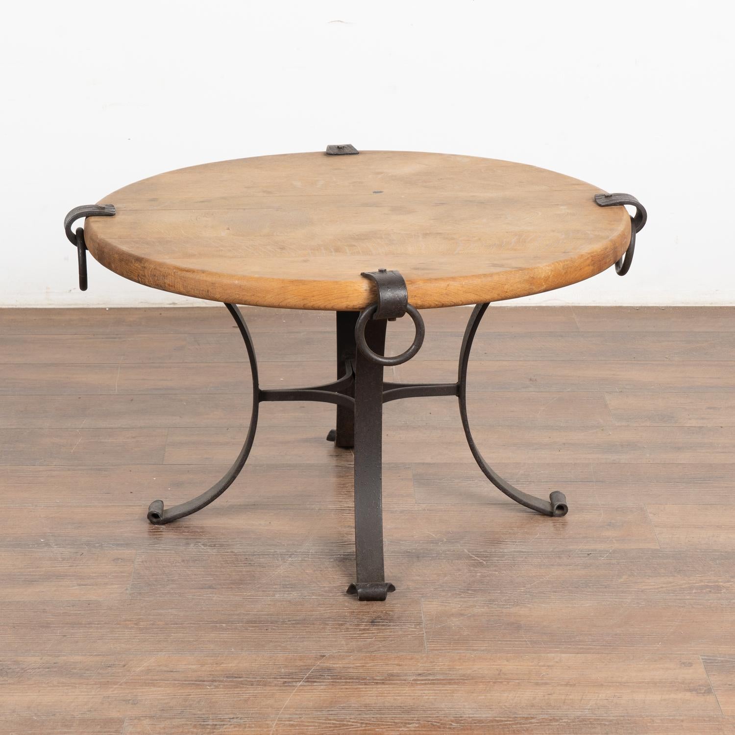 This rustic coffee table may also serve as a unique side table, thanks to the vintage iron rings, legs/base that accent the warm patina of the worn hard wood beech top. Typical age-related scratches, dings, minor separation of planks and multiple