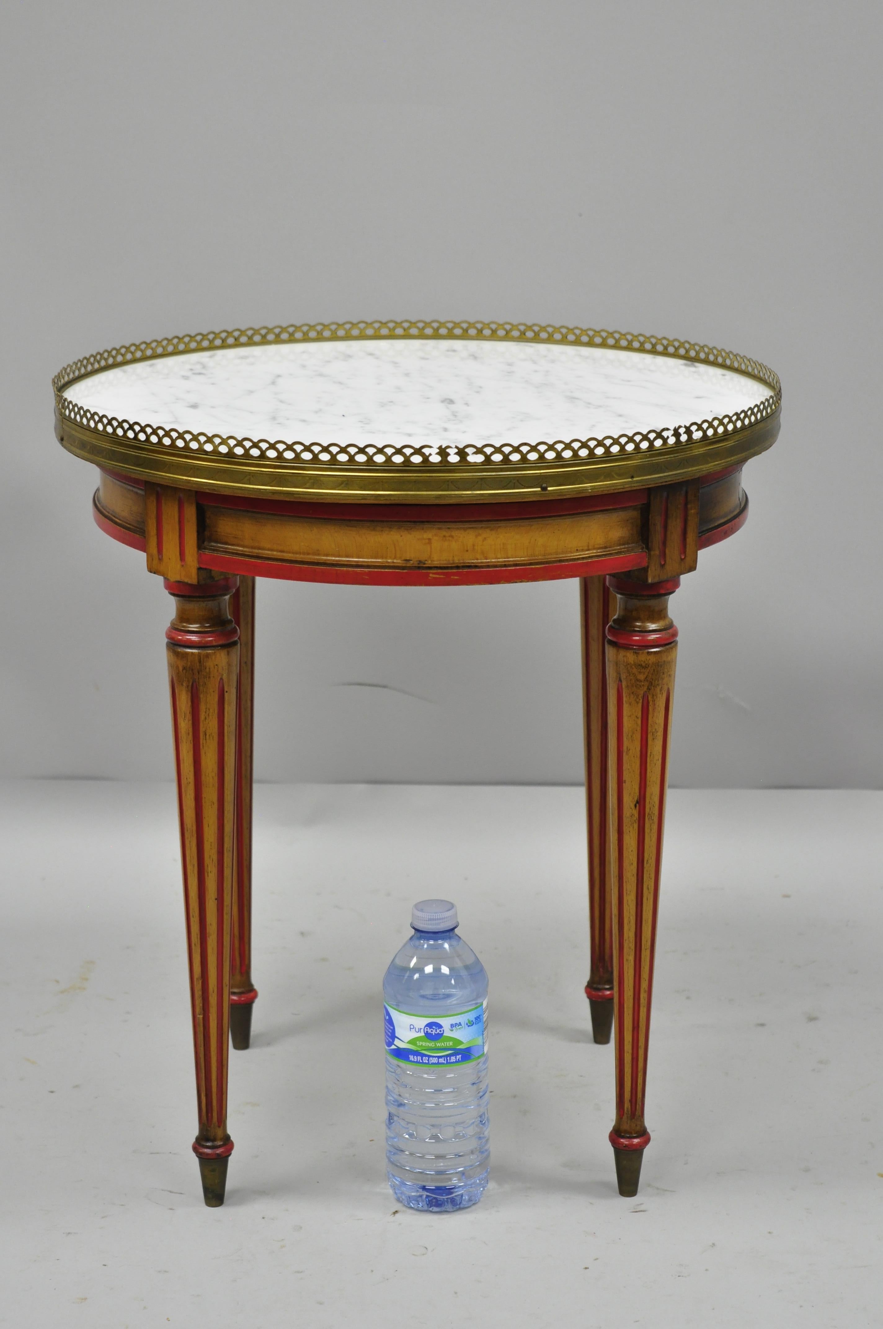 Small round marble-top French Louis XVI Directoire style Italian accent side table. Item features round inset white marble-top, red painted accents, brass gallery, tapered legs with brass feet, and stamped 