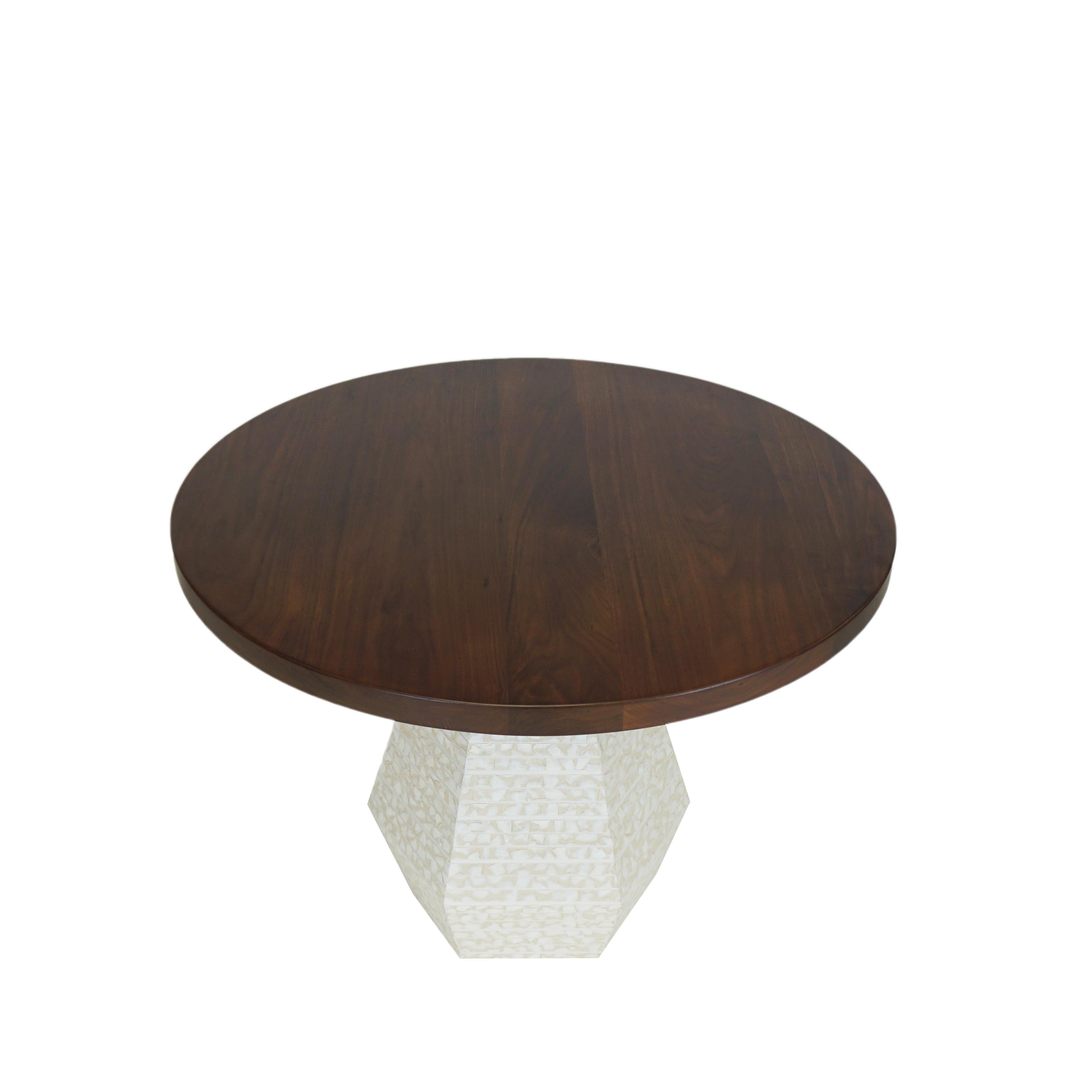 Our Capriz dining table is a modern round table with a walnut top finished in a satin lacquer. The hexagon shaped based is covered in Capiz shells, often referred to as “glass oysters” because of their translucent appearance. Custom sizes available.