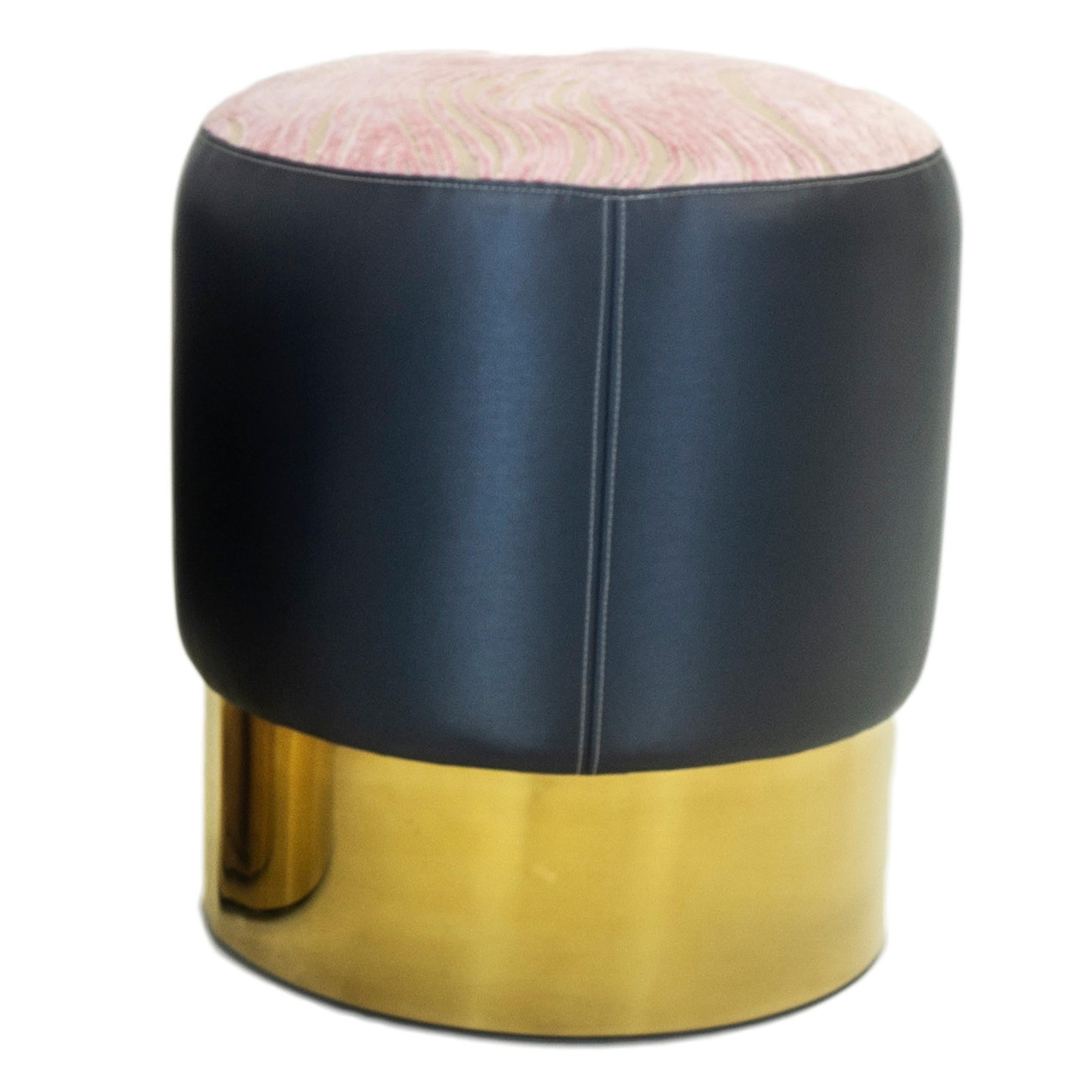 Our small round ottoman is the perfect finishing accent that can be used as extra seating. Featuring a round gold finished base, it is upholstered in a navy blue vinyl with pink cut velvet in a swirling pattern on top. Ask if any currently