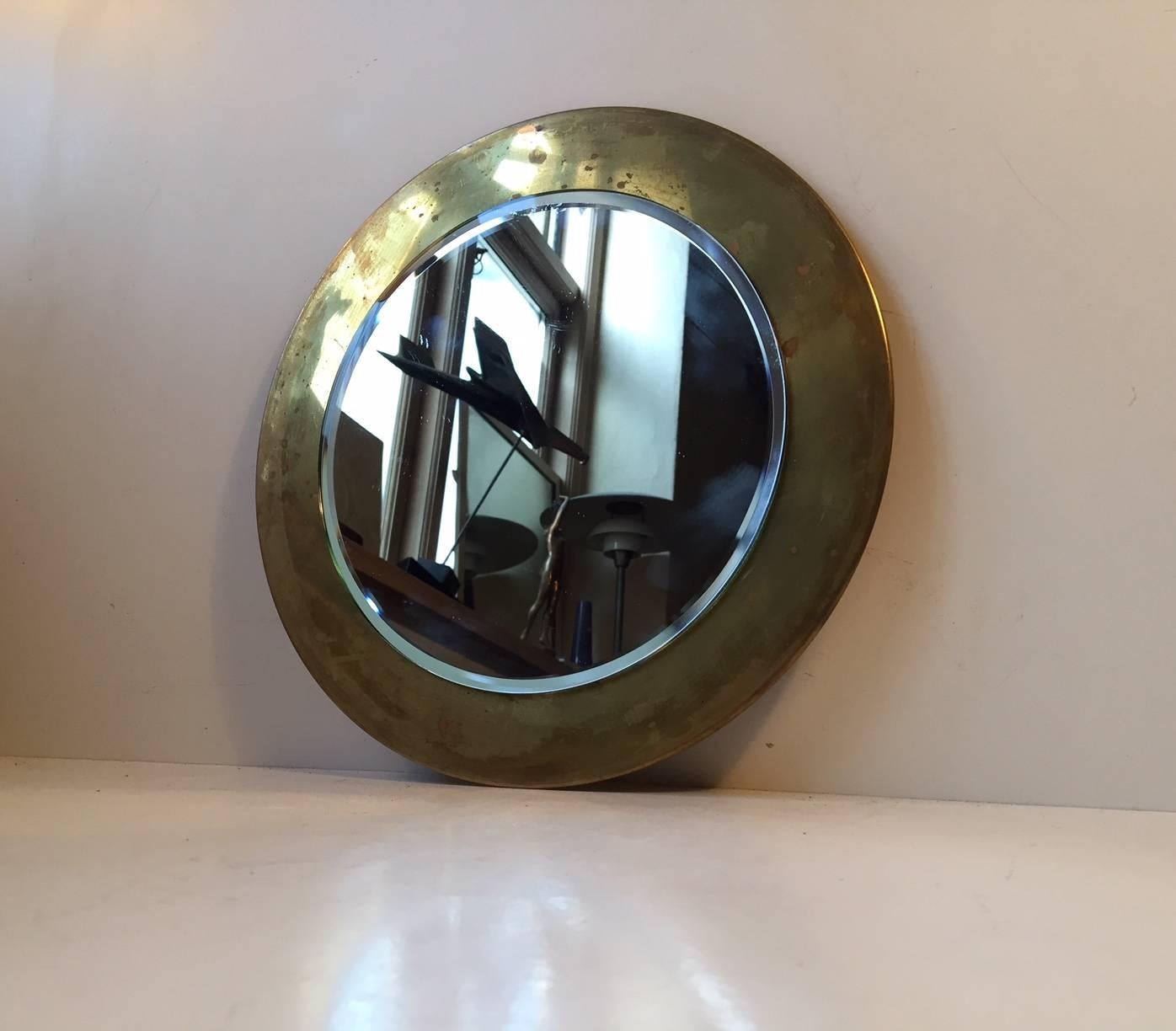 Small circular wall-mounted mirror composed of brass and mirror glass. The brass frame/backplate has patinated over the years but it’s still intact and without any damage. It was manufactured in Denmark during the 1960s in a style similar to Josef