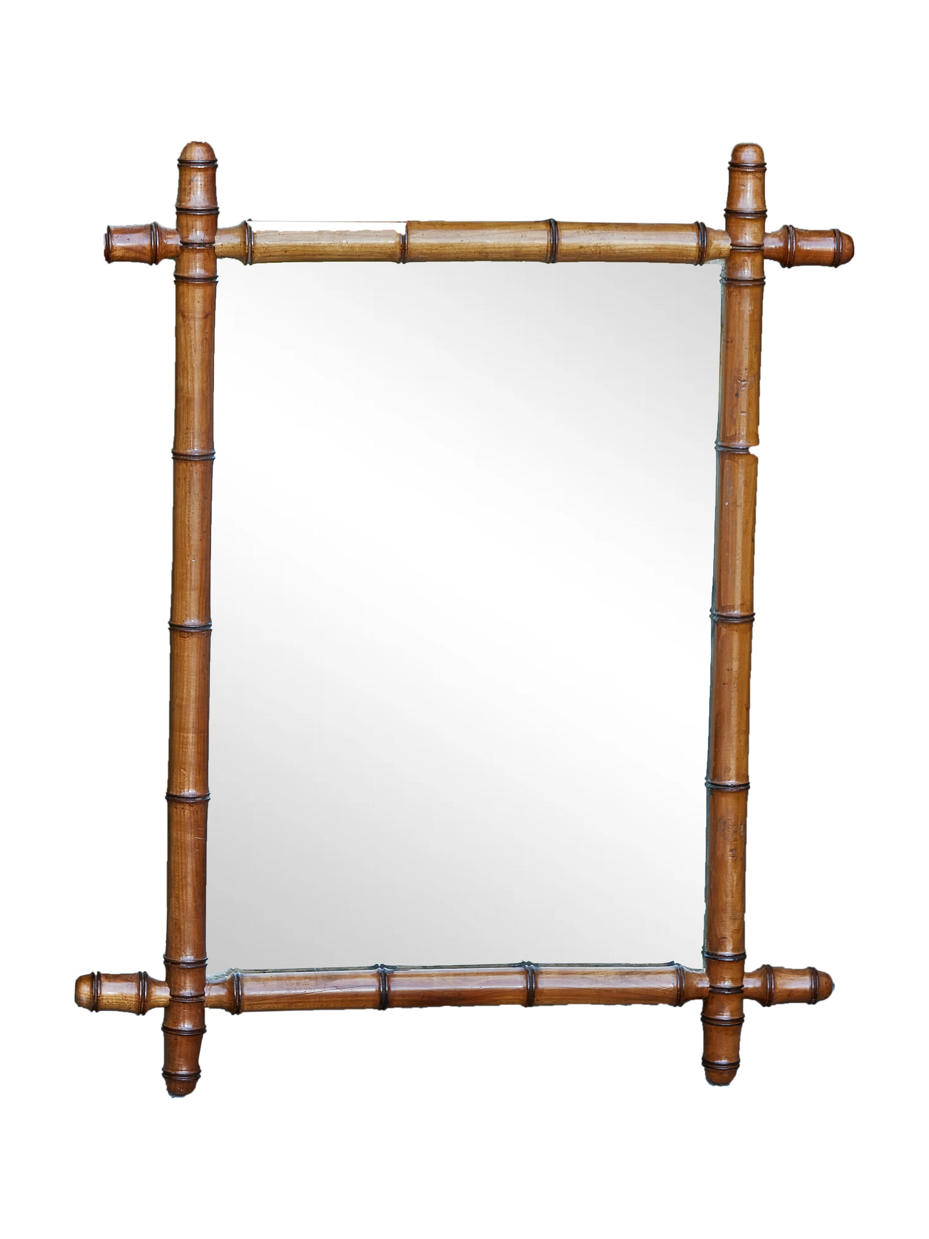 A small French faux-bamboo 1920s mirror made of walnut with intersecting corners, reeded accents and rustic character. Embrace the allure of the Roaring Twenties with this dainty French faux-bamboo mirror from the 1920s, a decorative gem that speaks