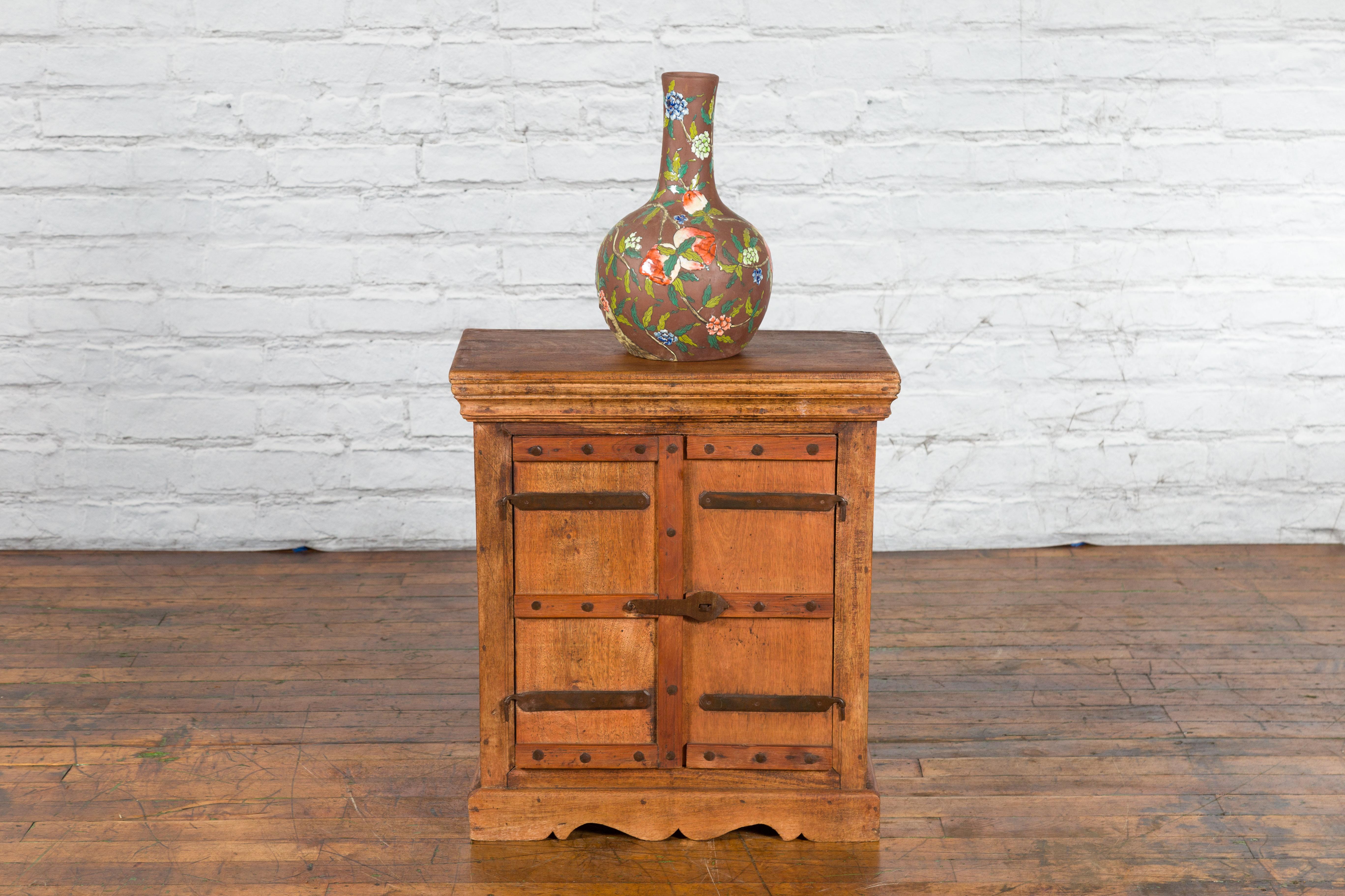 An Indian vintage sheesham wood single cabinet from the mid 20th century, with iron hardware, carved apron and natural patina. Created in India during the midcentury period, this small sheesham wood cabinet features a rectangular top sitting above