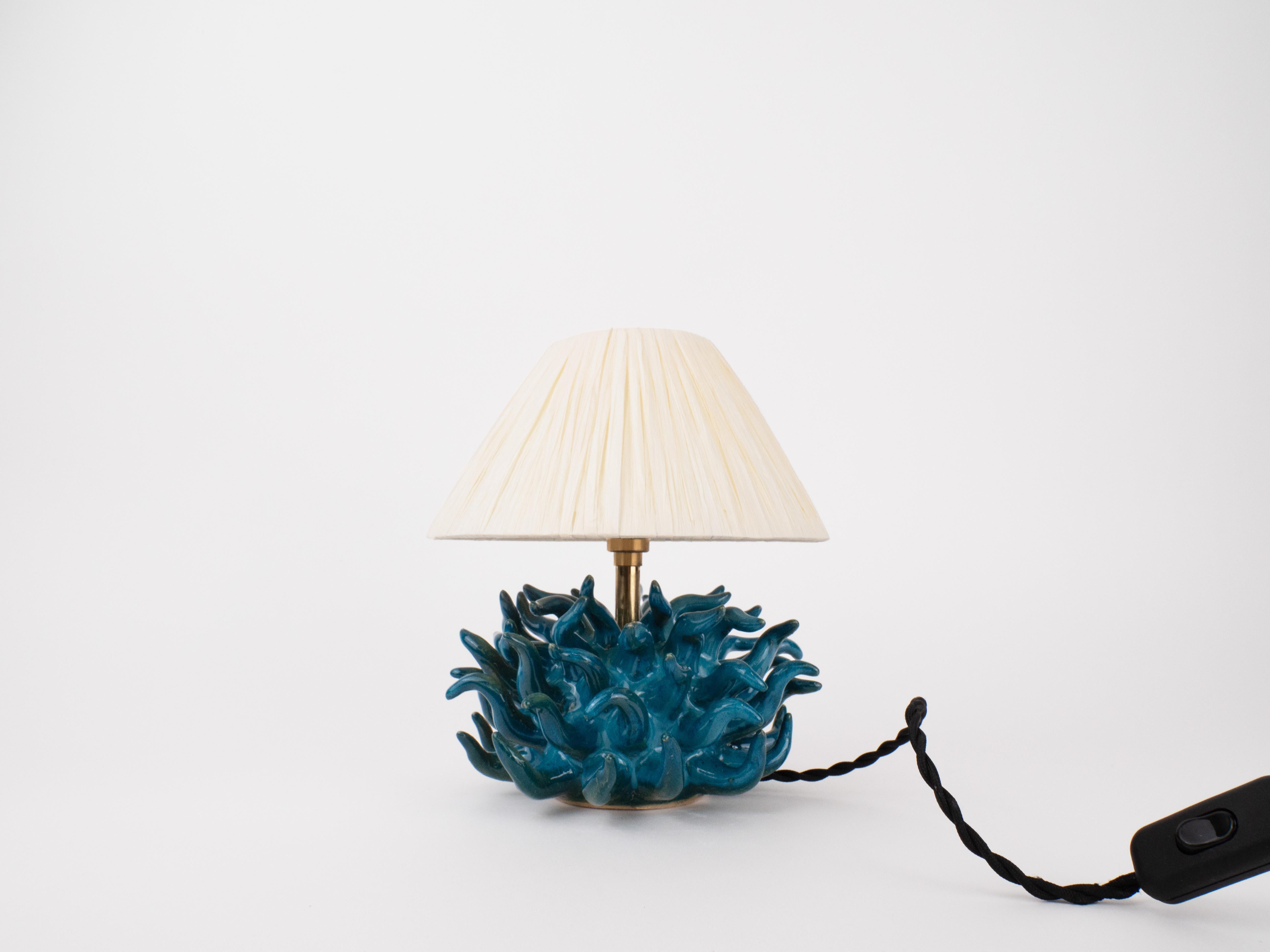 Make a bold statement with this striking lamp, featuring dynamic spikes radiating in all directions. The soothing sea green/blue color adds a calming, coastal vibe, while the playful design of the spikes creates an eye-catching focal point. 

Bulb