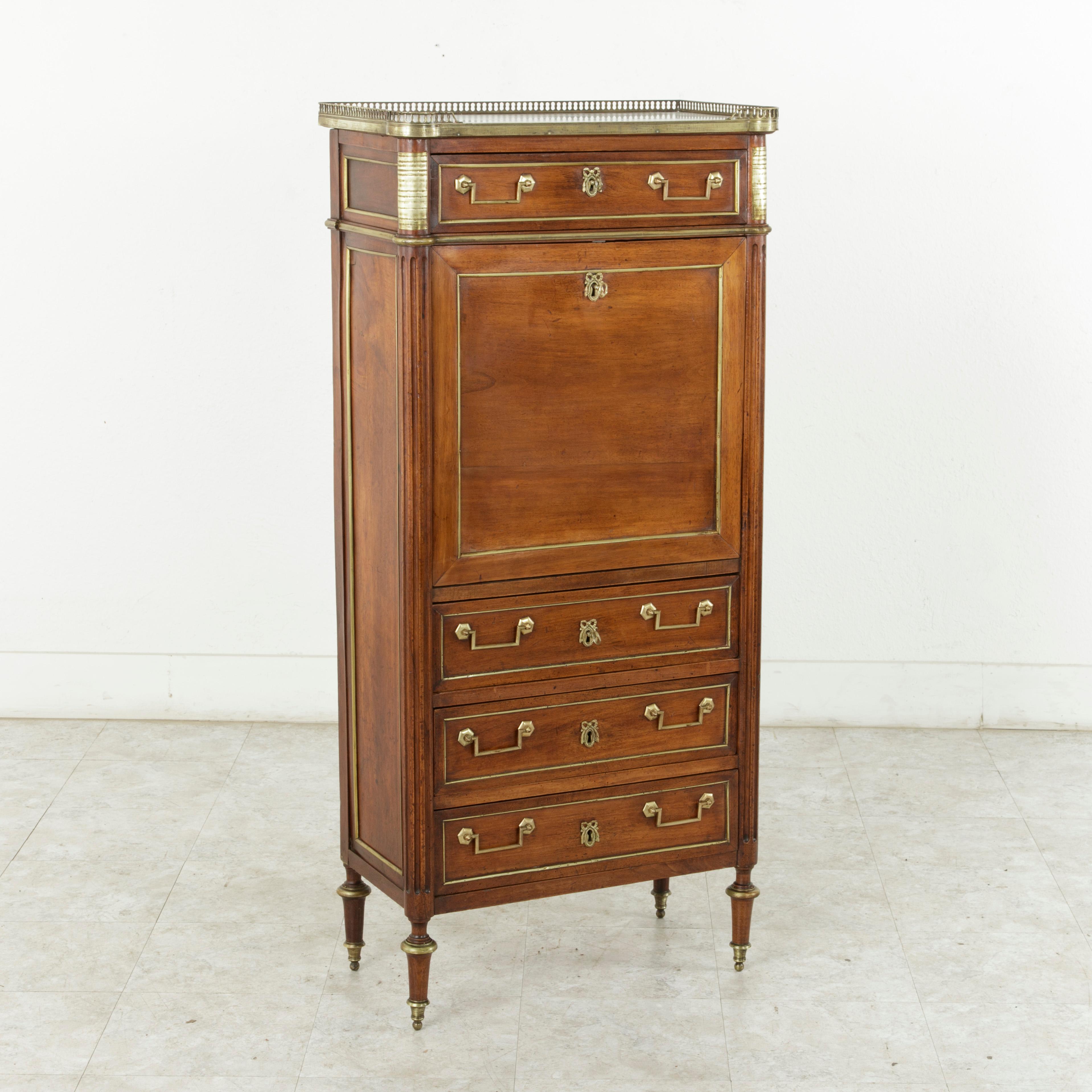 A rare period piece due to its small-scale, this eighteenth century French Louis XVI mahogany secretary features striated bronze plaques on the front corners and a pierced bronze gallery around its white marble top. Bronze banding defines each of