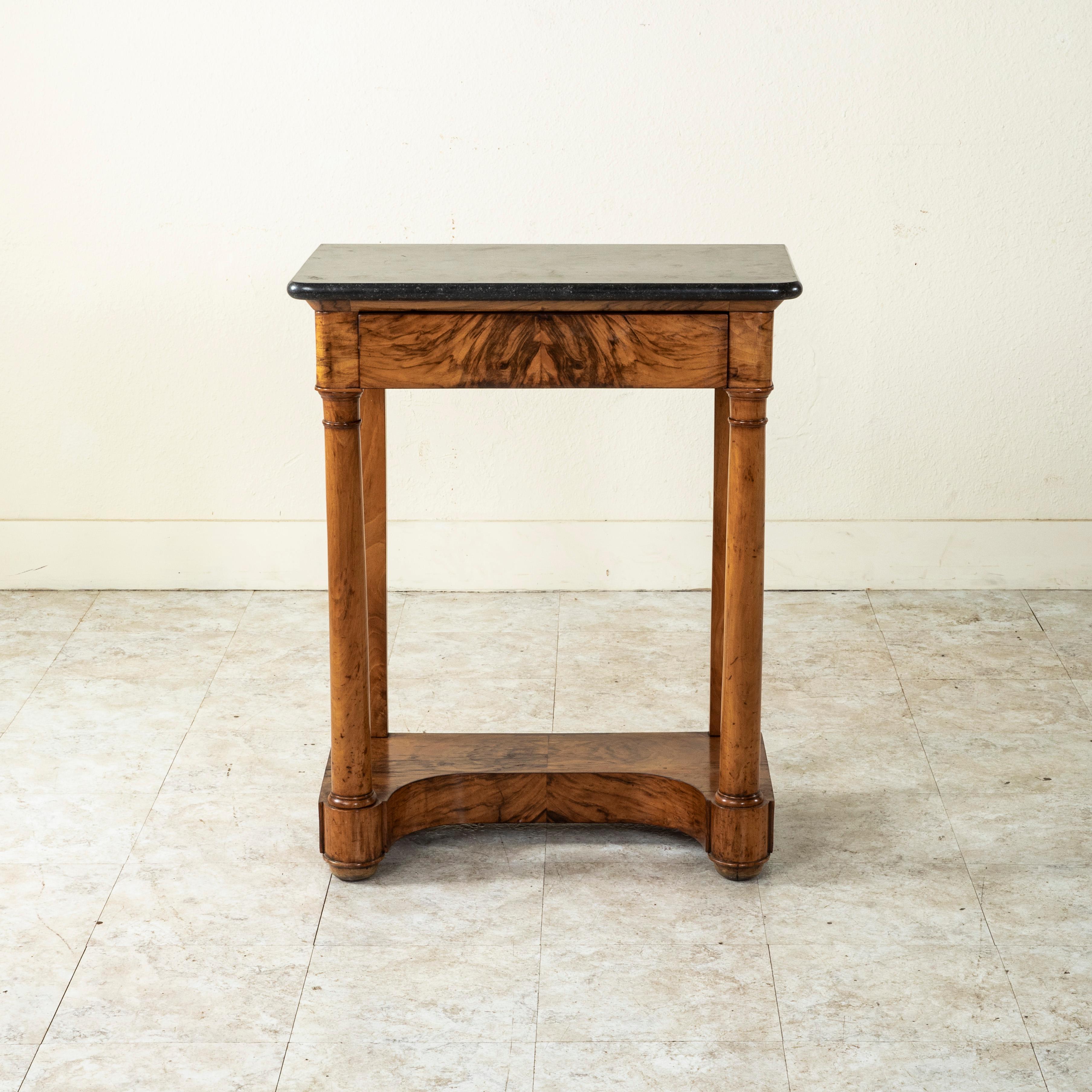 This early nineteenth century French Empire period book matched walnut console table features columns at the front corners and a Saint Anne marble top. A single drawer of dovetail construction fits seamlessly into the apron below the marble. The