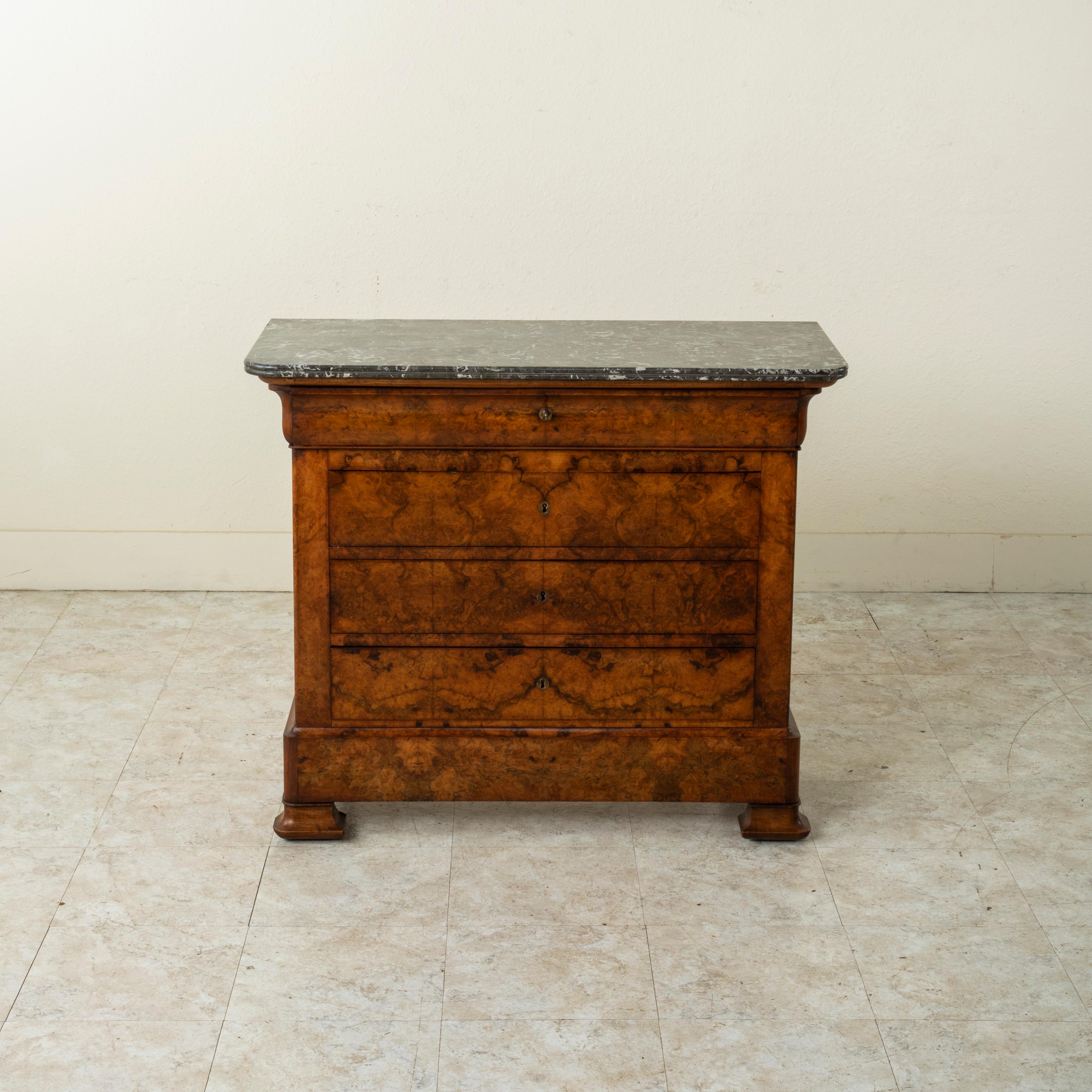 Rare for its smaller scale with a 38 inch width, this quintessential Louis Philippe period commode or chest of drawers displays the exemplary craftsmanship of the early 19th century with a facade of book matched walnut and solid walnut panel sides.