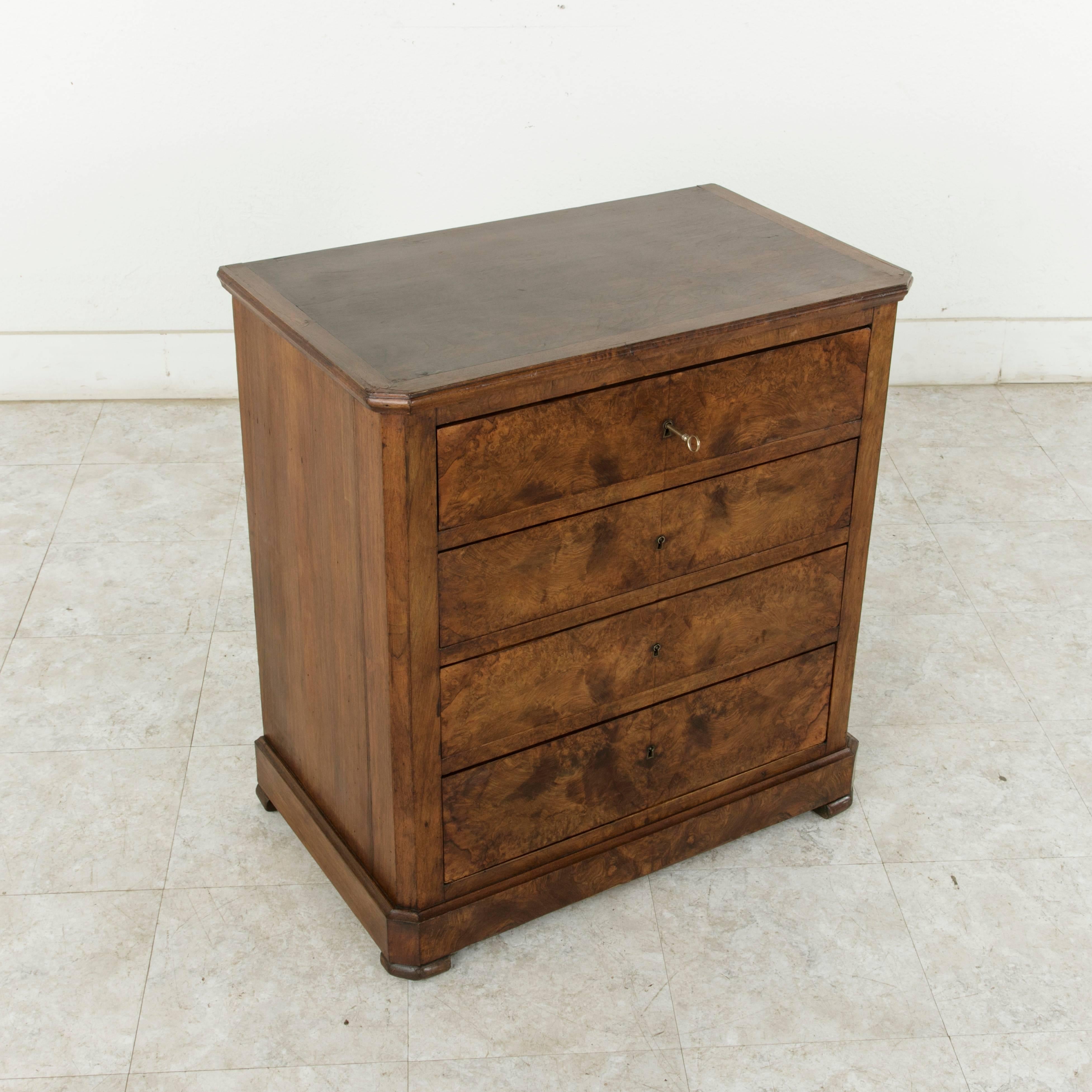Very rare for its small-scale, this 19th century Louis Philippe chest features walnut sides and top, and a bookmatched walnut facade with four locking drawers of dovetail construction. With its warm wood tones and simple lines, this handsome piece