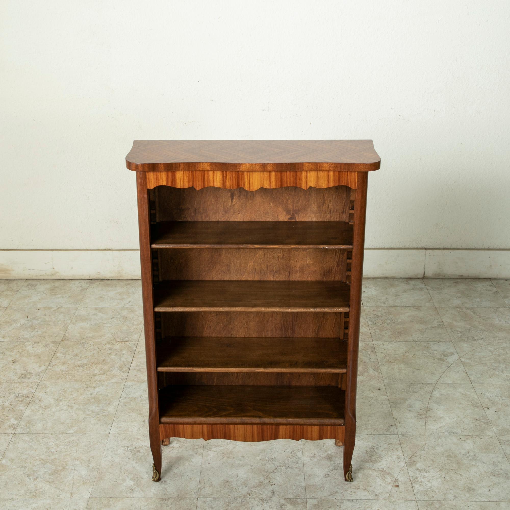 Standing at only 38 inches in height, this small scale early 20th century French Louis XV-Louis XVI transition style bookshelf features an exquisite inlaid rosewood exterior. Its three shelves are adjustable to accommodate different heights. The