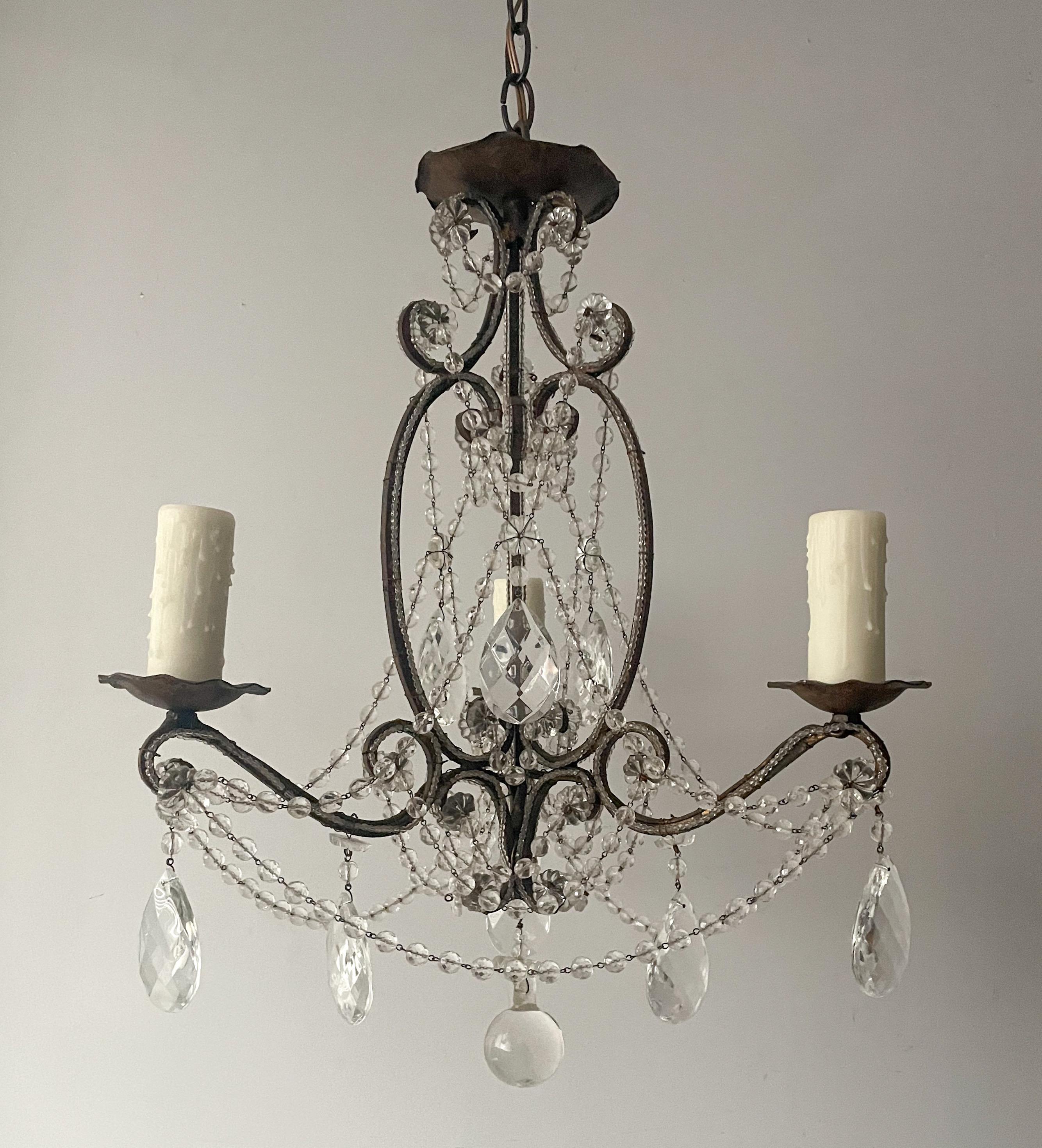 Beautiful, small scale Italian gilt-iron and crystal beaded chandelier. 

The chandelier features a scrolled iron frame in a dark bronze paint finish and crystal decorations. 

The chandelier is wired and in working condition, it requires 3