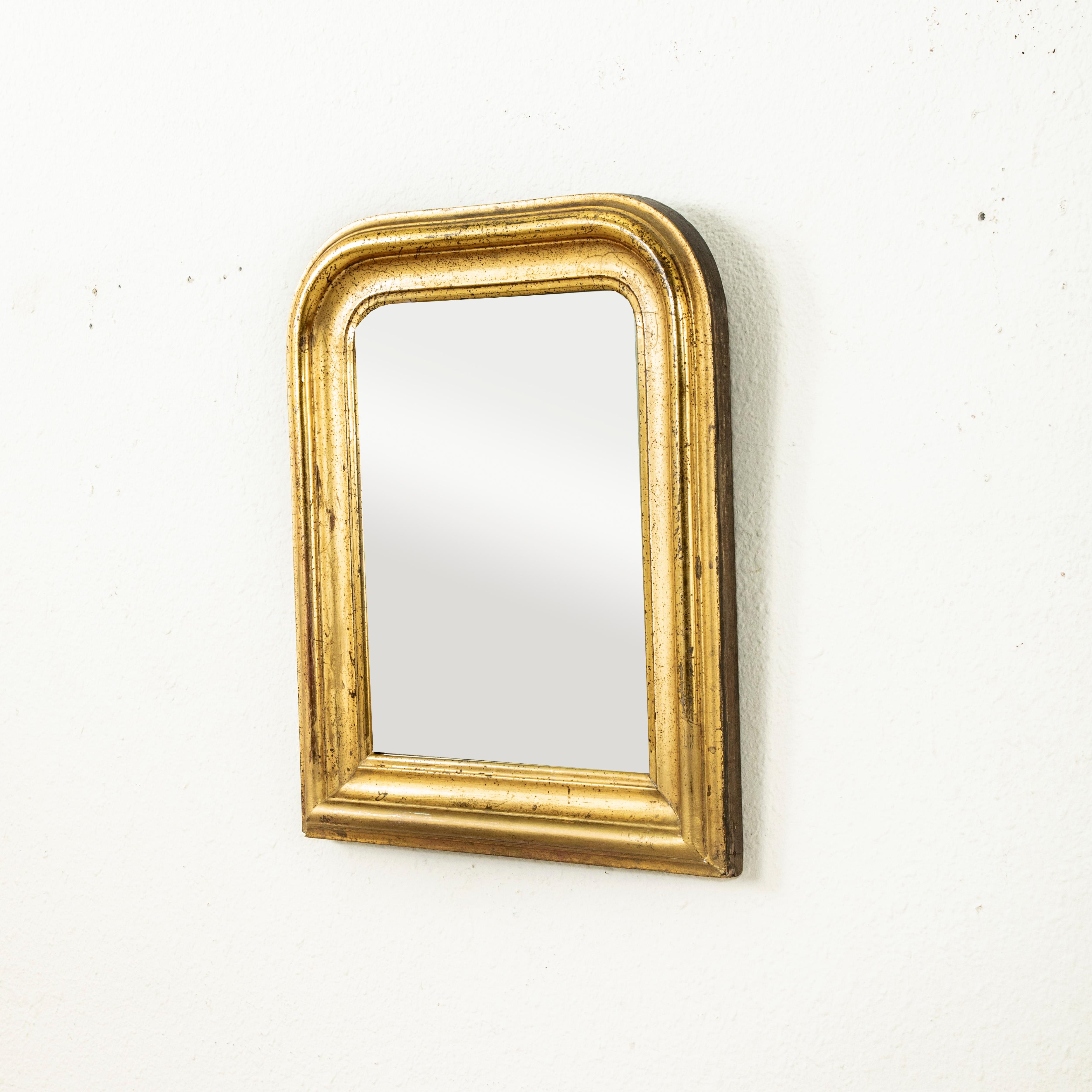 Measuring only 20.5 inches in height by 16.75 inches in width, this small scale nineteenth century Louis Philippe period gilt wood mirror features its original mercury glass. Its beveled pillow frame boasts a patina that only comes with age. An
