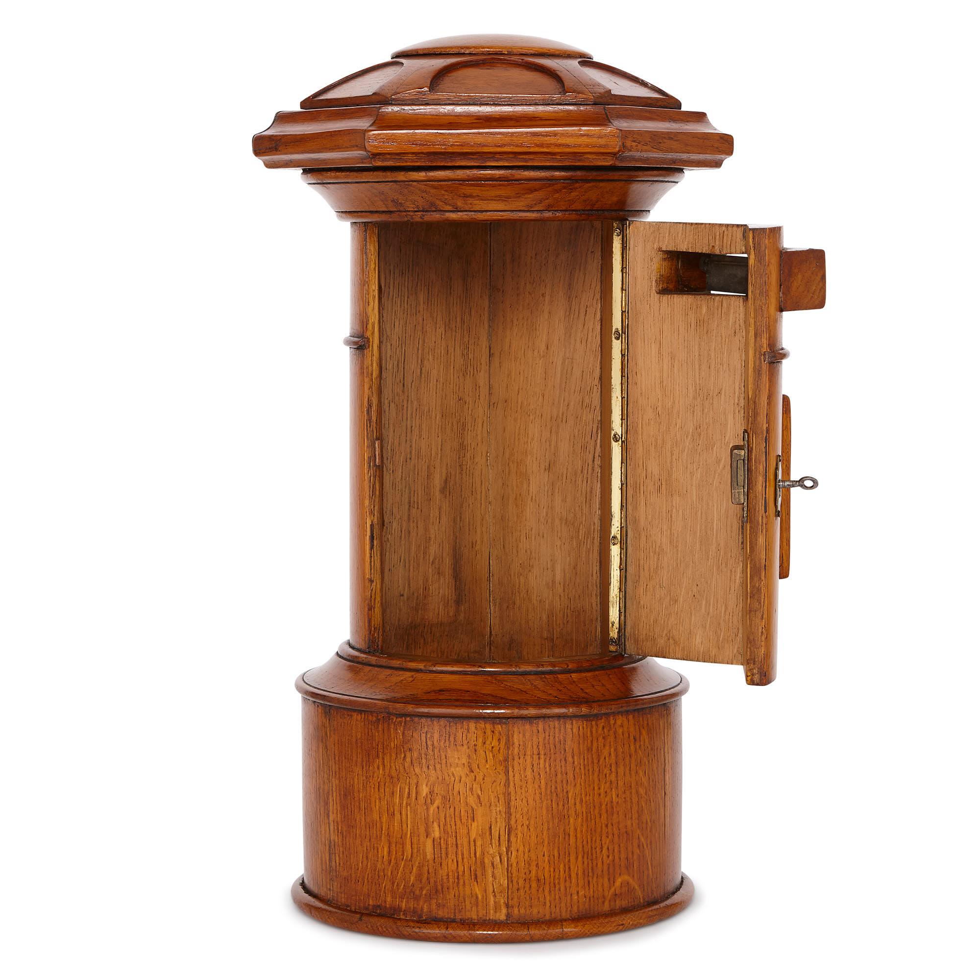 This small, oak pillar letter box was crafted in England in the early 20th century. It is likely the piece was created for a country house, where it would be used to store letters before a servant collected and delivered them to the post office to