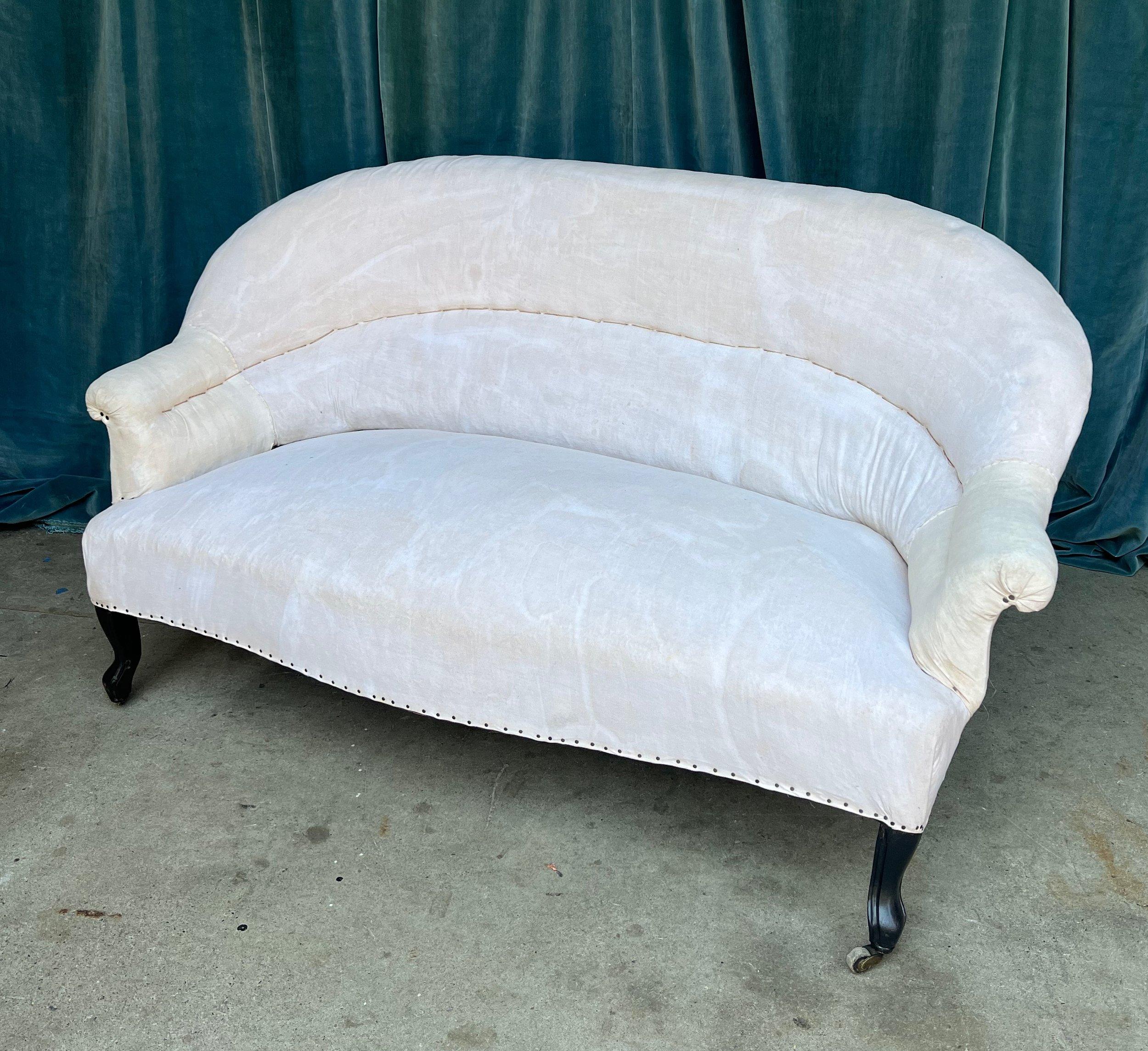 An elegant French early 20th century small scale settee in the Napoleon III style. This French settee is a timeless piece of furniture that embodies classic elegance. Its gracious curved back with built-in lumbar support and rolled arms are typical