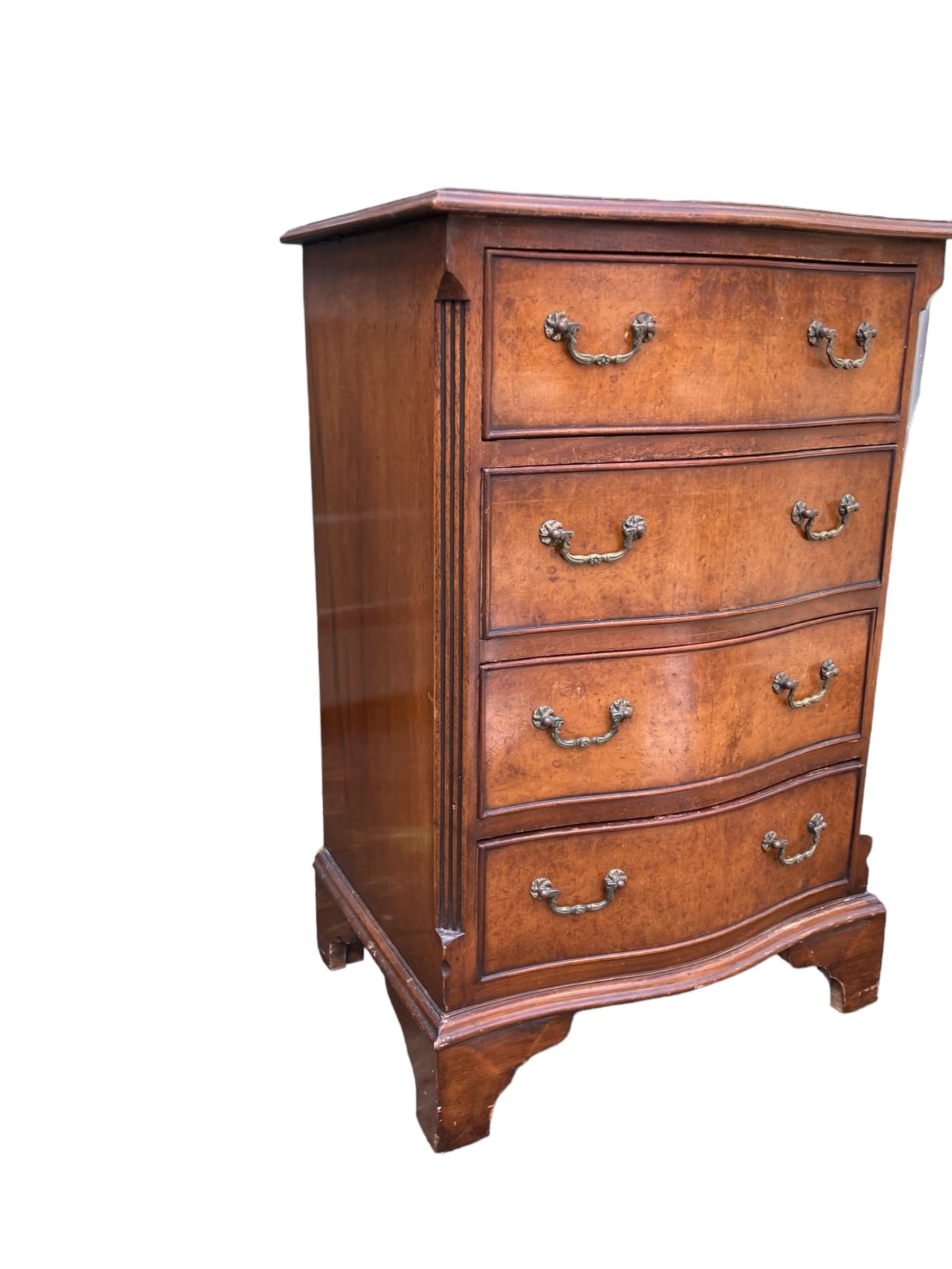 Small serpentine burr walnut veneered chest of drawers, burr walnut veneered top with cross banded border. It has four drawers with brass drop handles. It stands on bracket feet. Polished walnut sides and solid back. A beautiful example. Early 20th