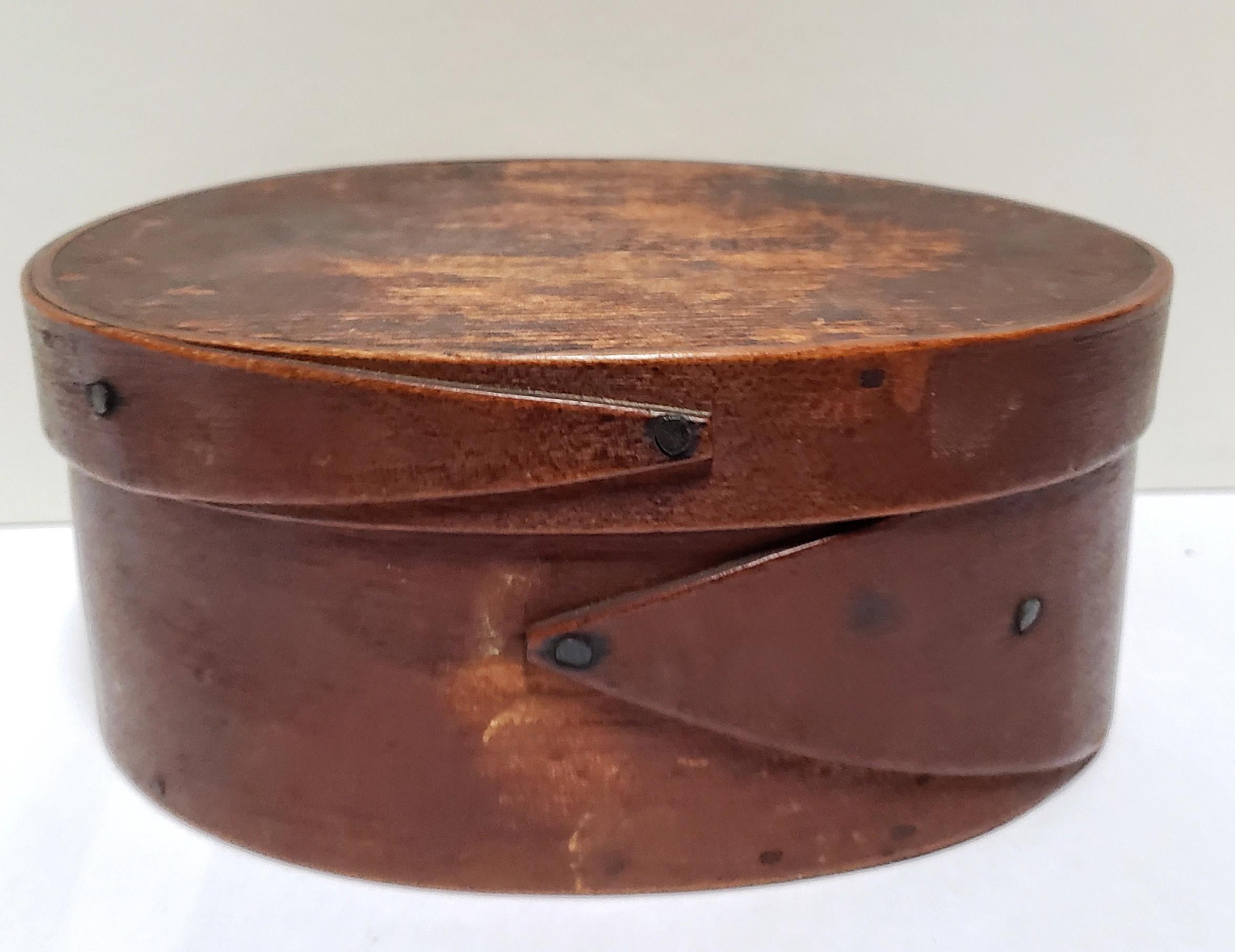 A single lap-jointed bent-wood Shaker oval pantry box with fine old patina. The laps are secured with iron tacks, while the top and bottom boards are wooden pegged. The wood is richly colored by a century and a half of use. The box was made in the