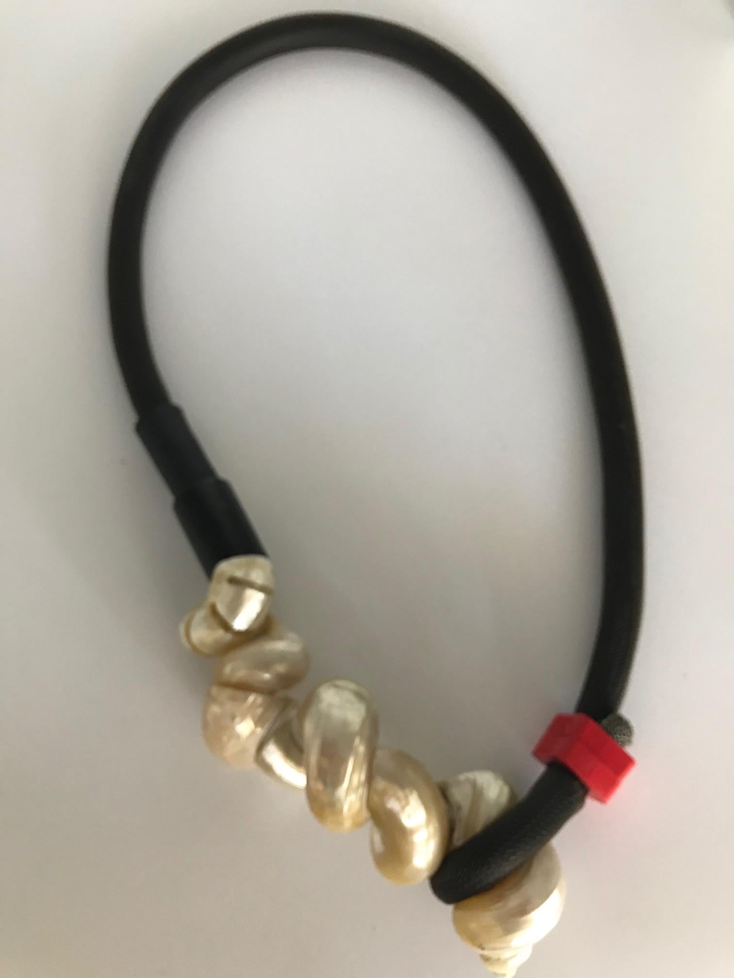 
This is a Pendant of Small Turbo Shells on a Rubber Tube. Designing with small and medium shells is a labor of love because  pearl producing oysters will be cultured even when the oceans become too acidified for their survival. However, it is