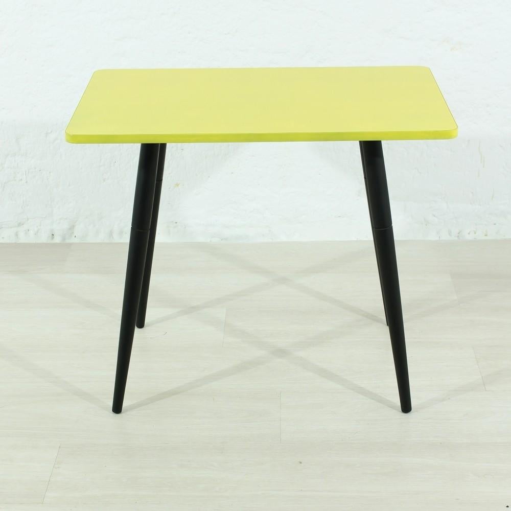 This small wooden side table in yellow remains in a stable condition.