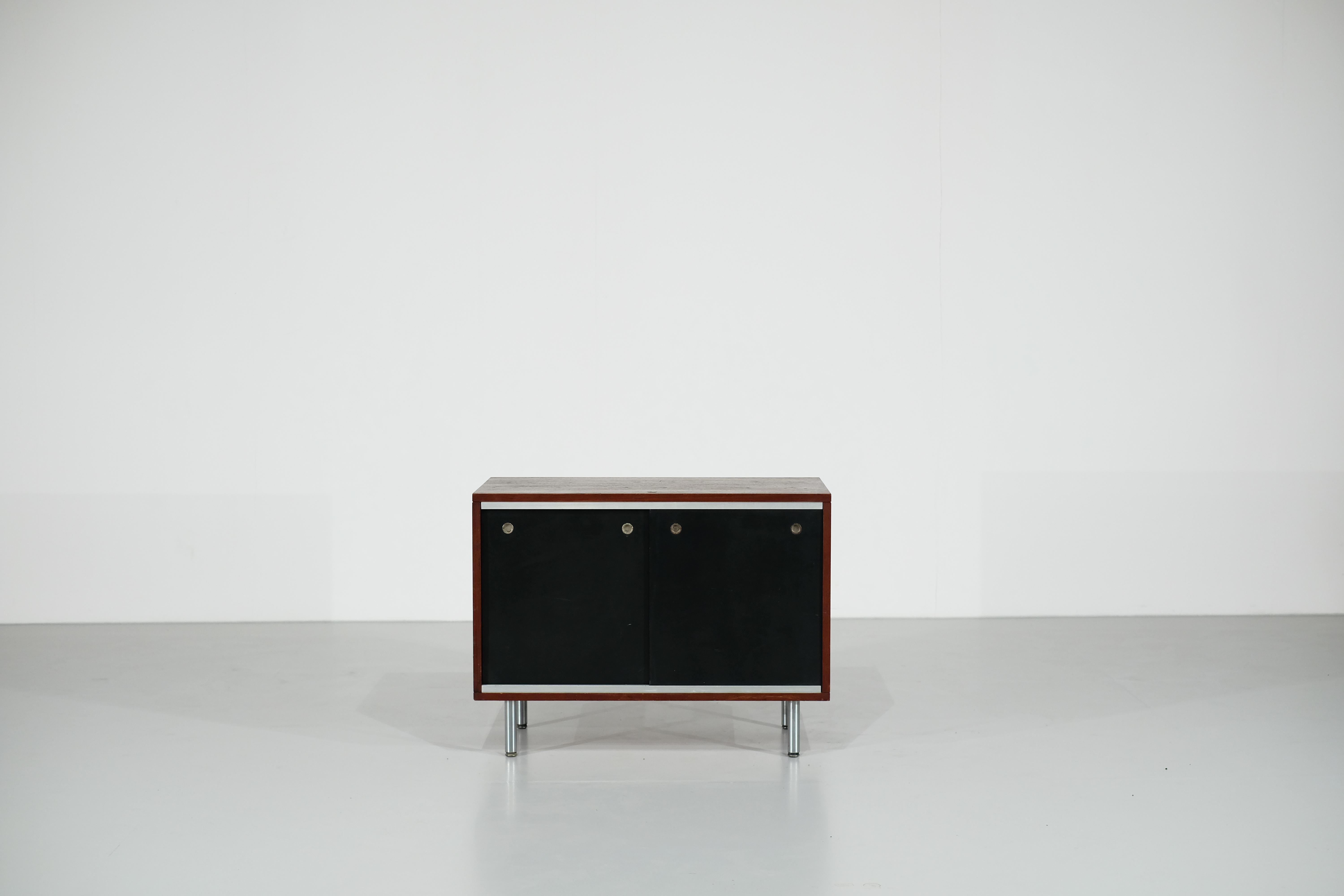 Amazing small sideboard by George Nelson for Herman Miller in the 1970s.

It is made up of 2 black sliding doors and metal handles.
It also has a shelf on each side that can be adjusted according to needs and desires.
The feet are in chrome