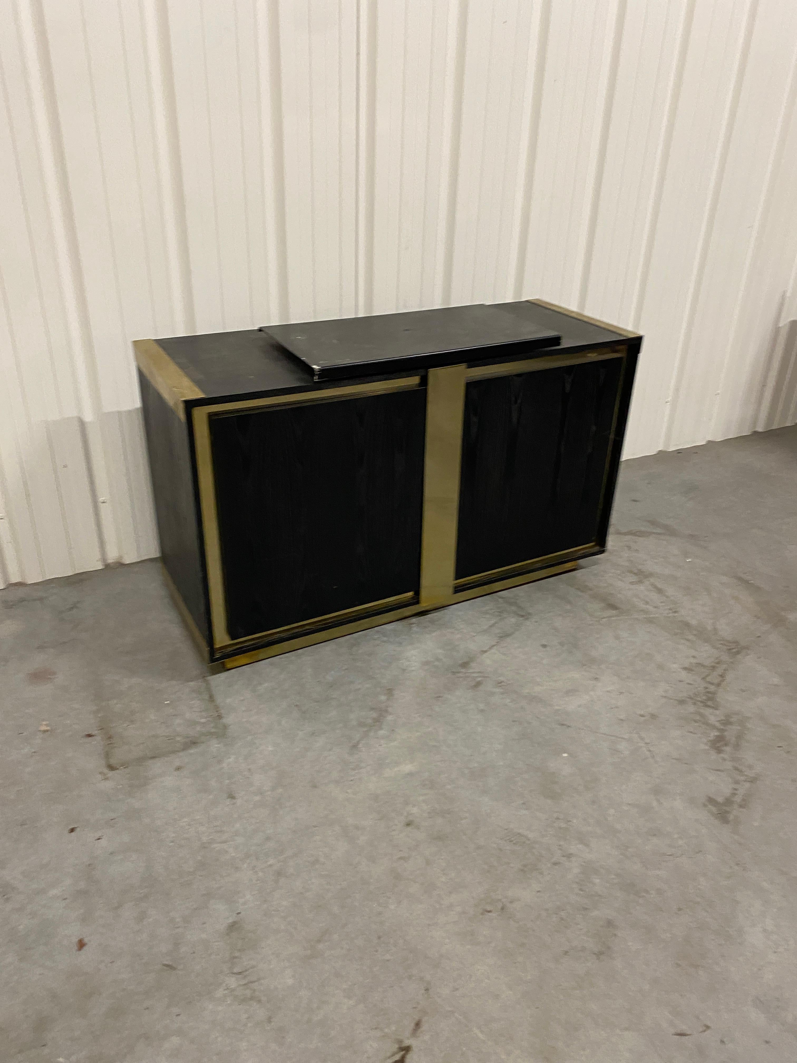 Small sideboard in blackened oak and brass circa 1970
currently equipped with a sliding and rotating tray to place a television, a computer, etc.
two glass shelves inside