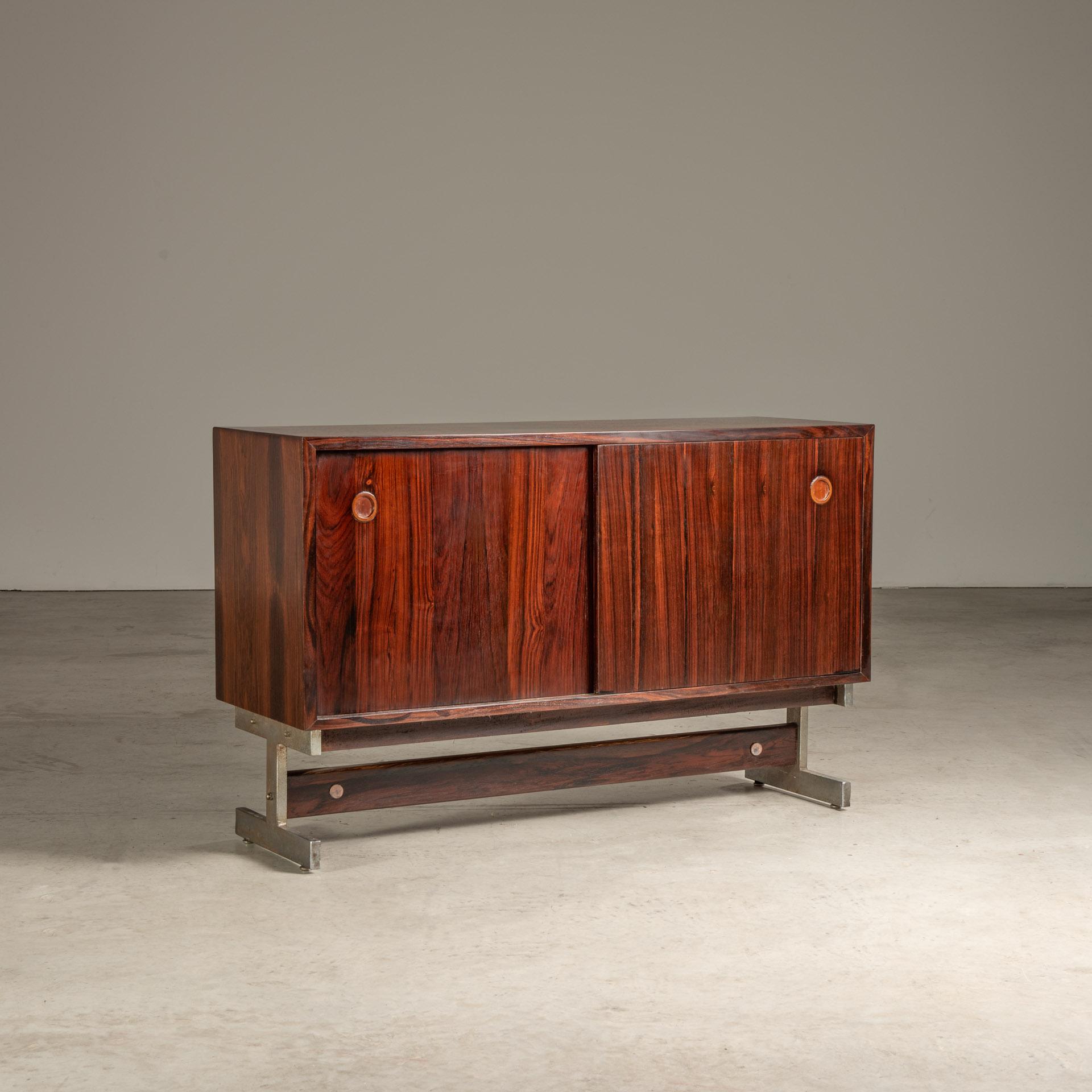 This meticulously crafted sideboard by Sergio Rodrigues is a paradigm of Brazilian mid-century modern design, seamlessly integrating functionality with a striking aesthetic. The structure stands on a robust yet elegantly minimal steel frame, which