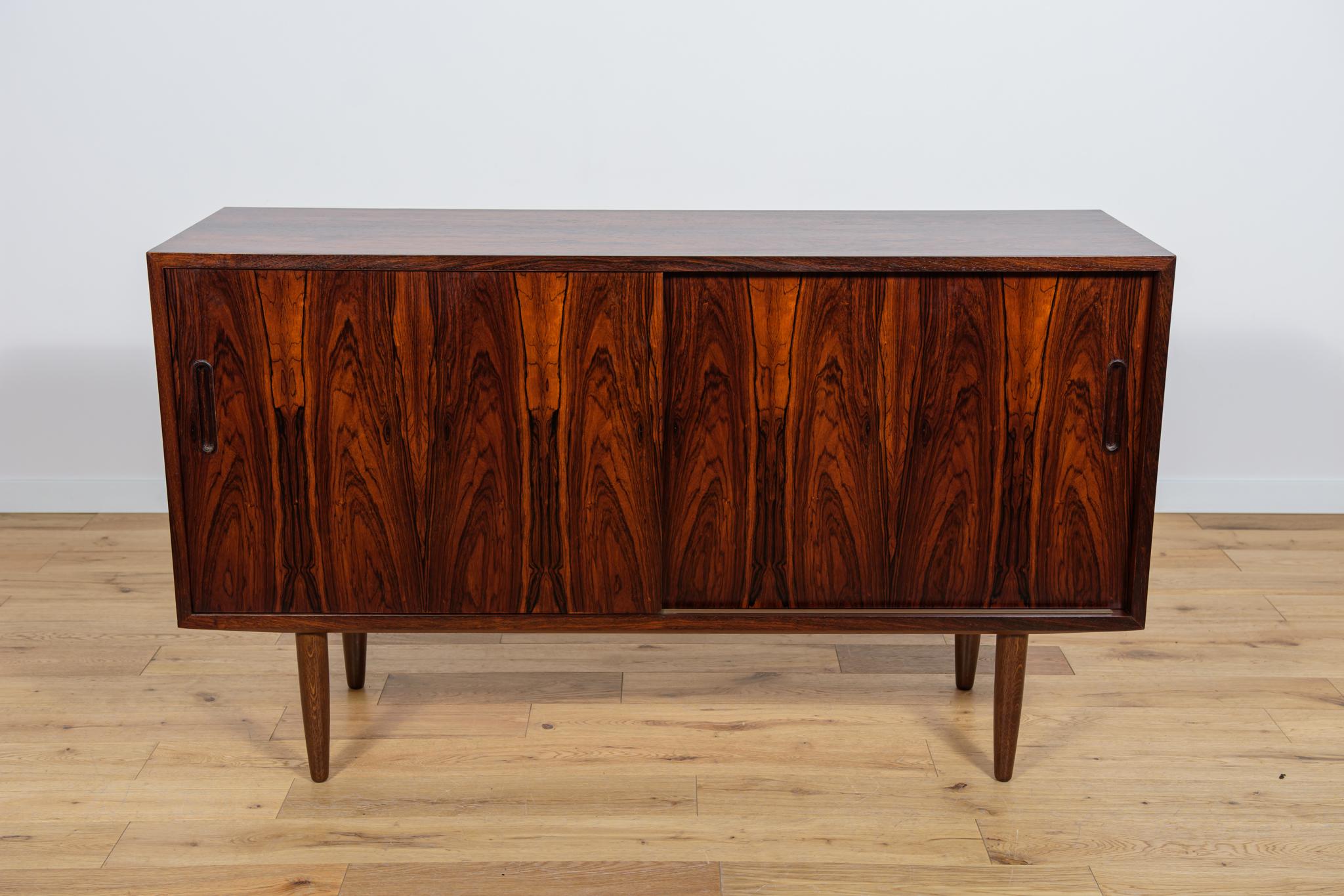 This is a small sideboard designed by Poul Hundevad in the 1960s. It was manufactured by the Hundevad & Co furniture factory in Denmark. Sideboard with two sliding doors, inside there are adjustable shelves and one drawer. The furniture is