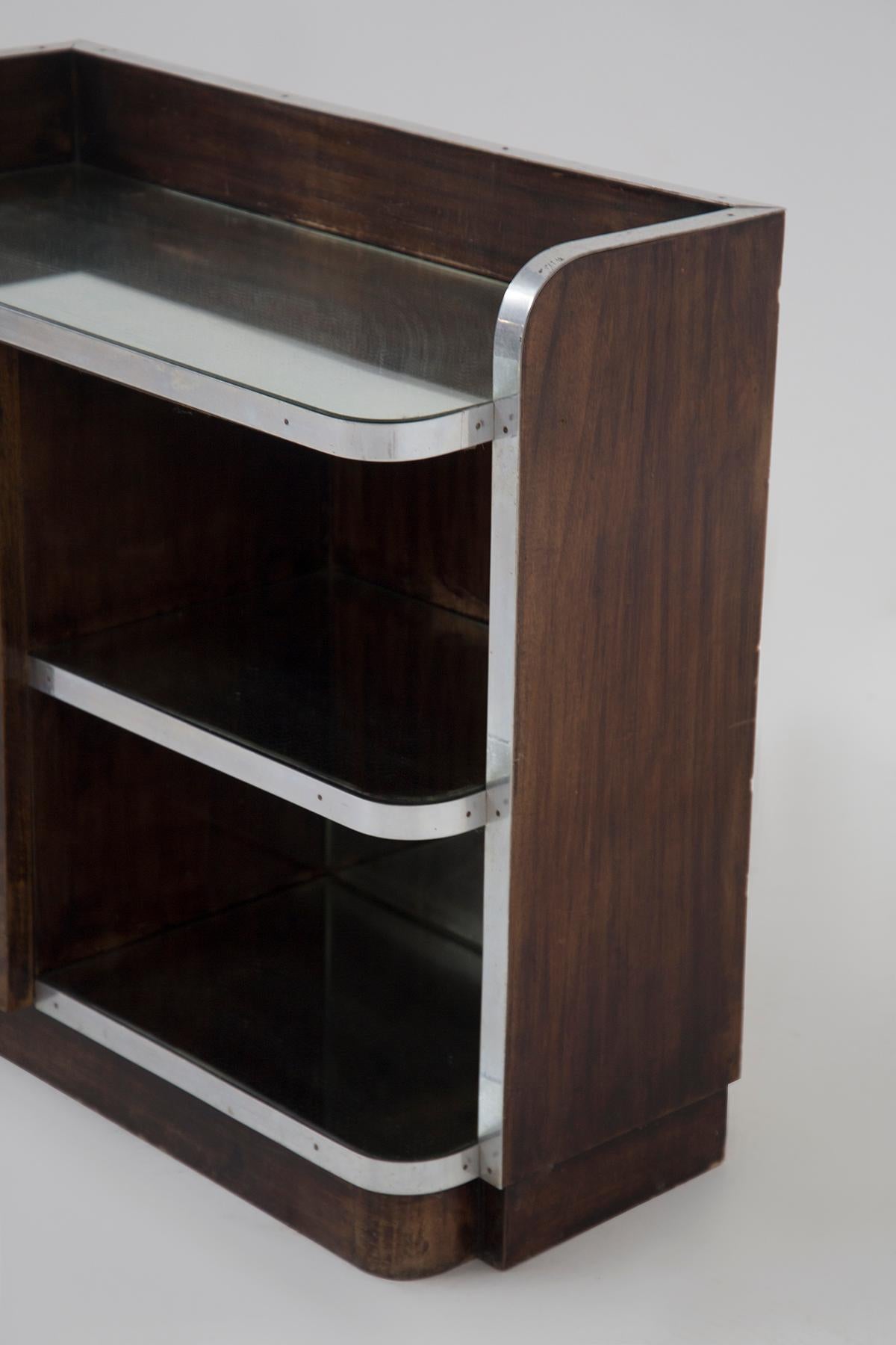 This cabinet is a remarkable example of Bauhaus-inspired design, showcasing a harmonious blend of wood, iron, and reflective glass shelves. Crafted during the iconic period of rationalist design in Italy, this piece exemplifies the essence of