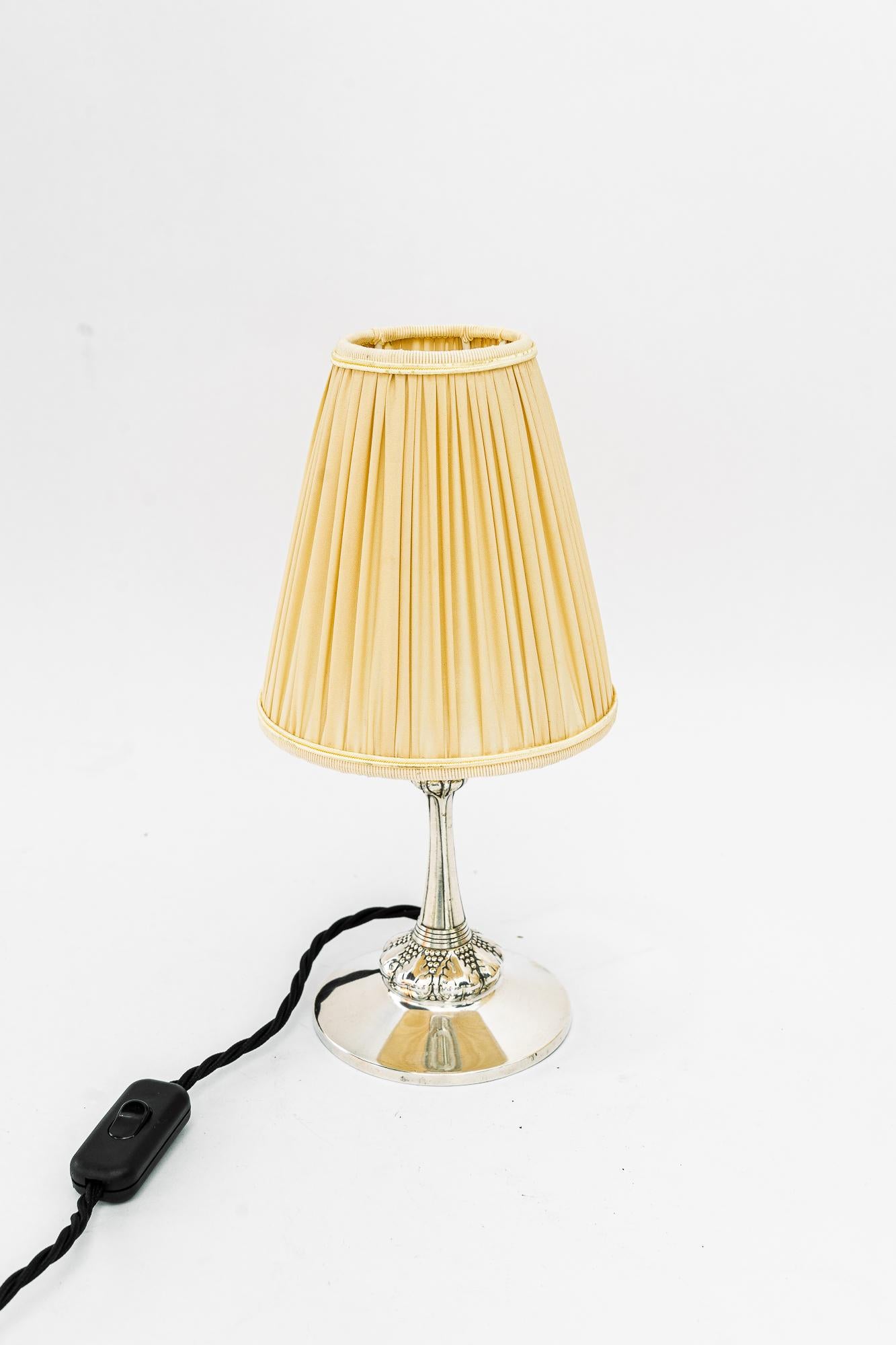 Kleine versilberte Art Deco Tischlampe mit Stoffschirm Wien um 1920er Jahre
Der Stoffschirm wird ersetzt ( neu )
Ursprünglicher Zustand