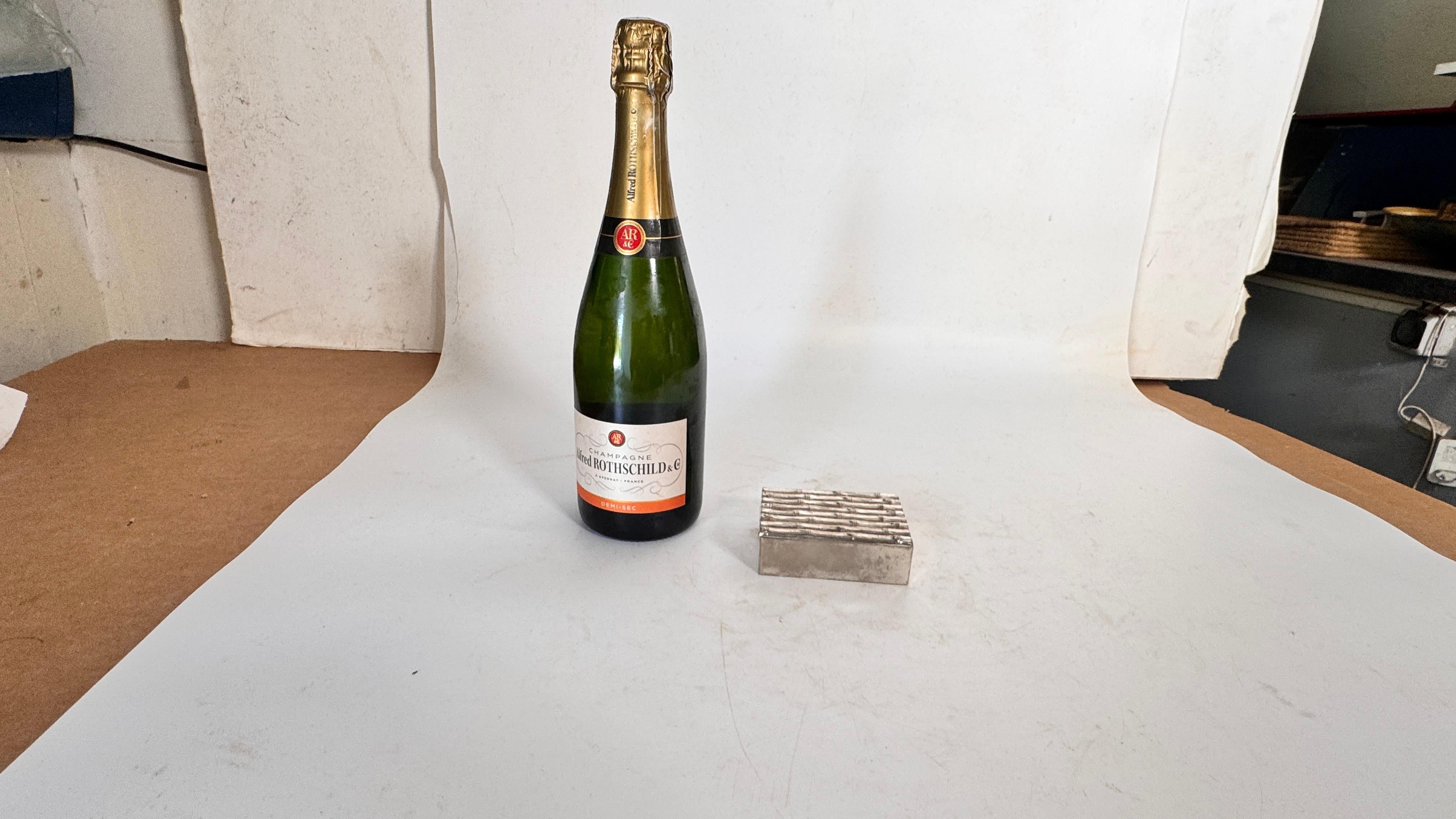  Joyero pequeño de metal plateado - Motivo juncos - Francia, años 70

Descripción:
Se trata de un pequeño joyero decorativo fabricado en Francia en la década de 1970, de metal plateado. La tapa está adornada con un motivo repetido de cañas, que da a
