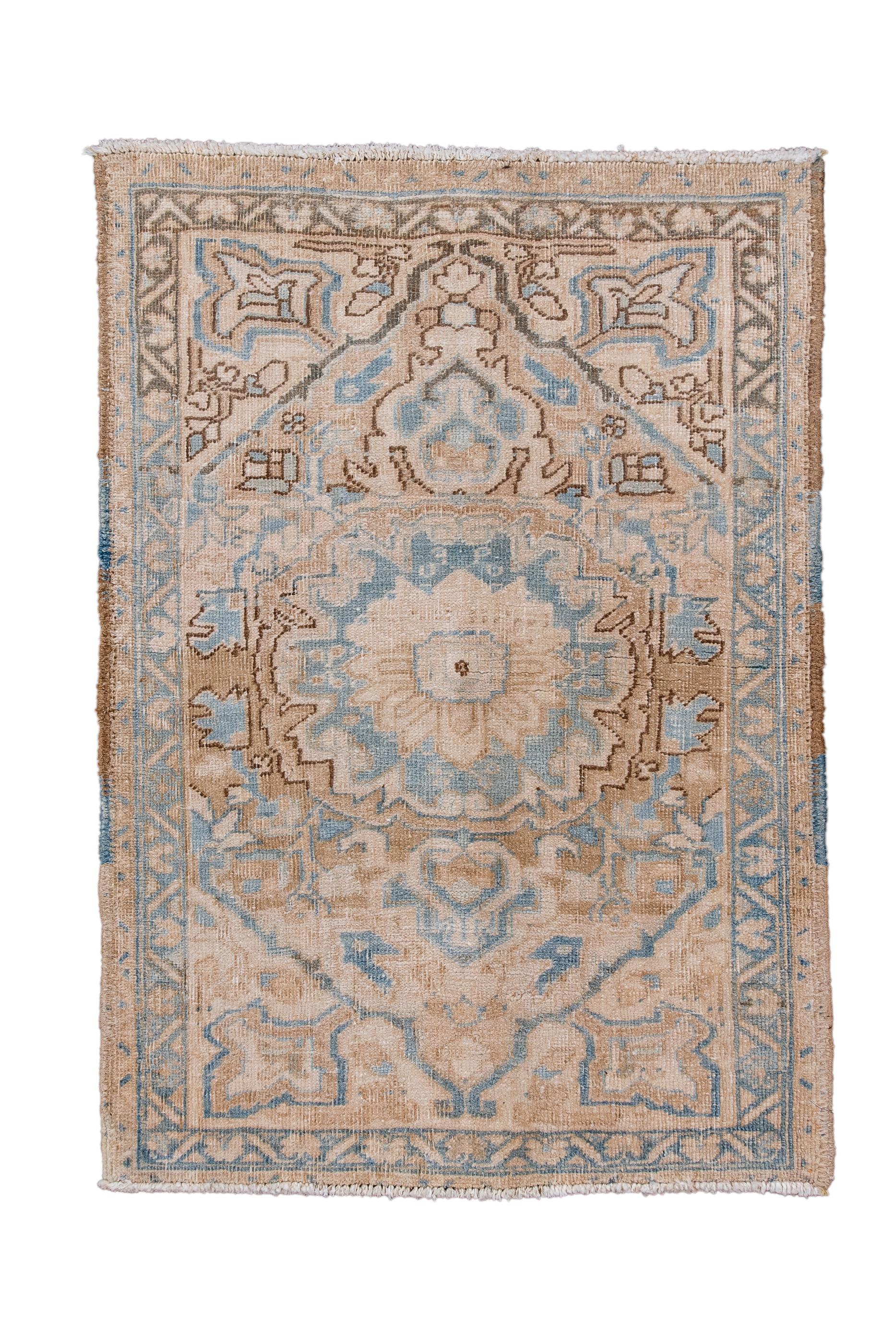 This diminutive rustic rug shows a muted palette of rust,  pale blue and cream, expressed in a lobed and pendanted medallion set on a pointed field with pointed, radiating floral corners. Abrashed blue border with reversing fan palmettes.